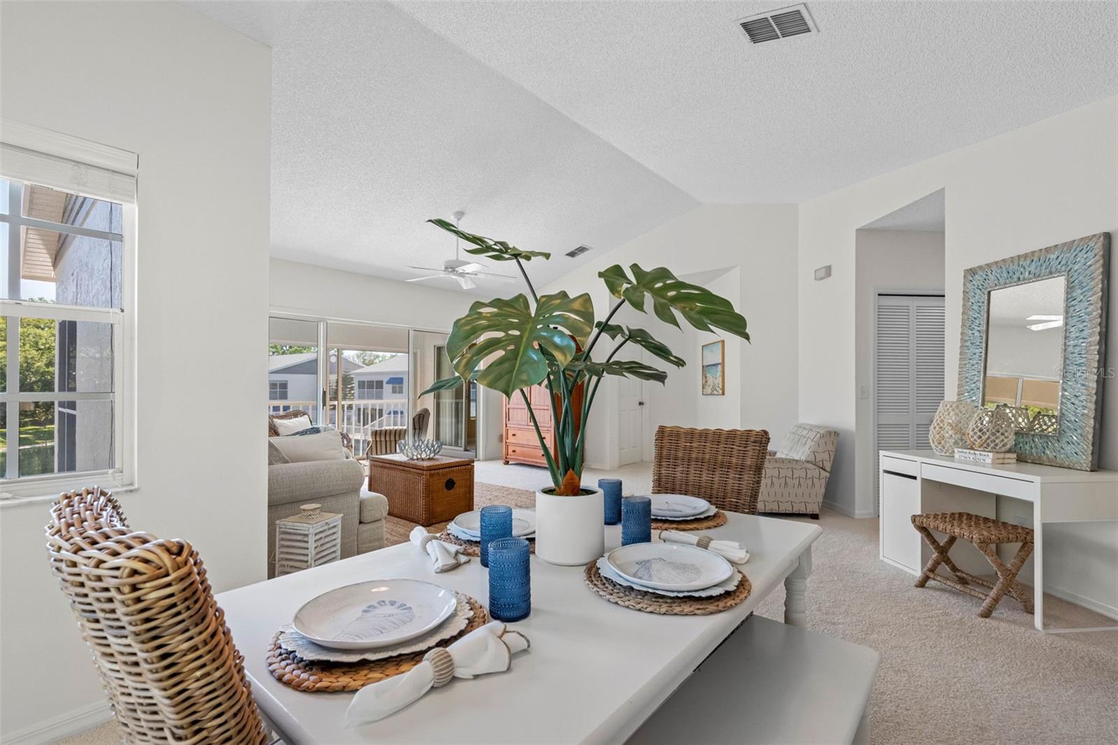 .. Dining Area Looking into the Living Area. Guest Bedrooms & Laundry Down Hallway Next to Mirror with Blue Highlights.