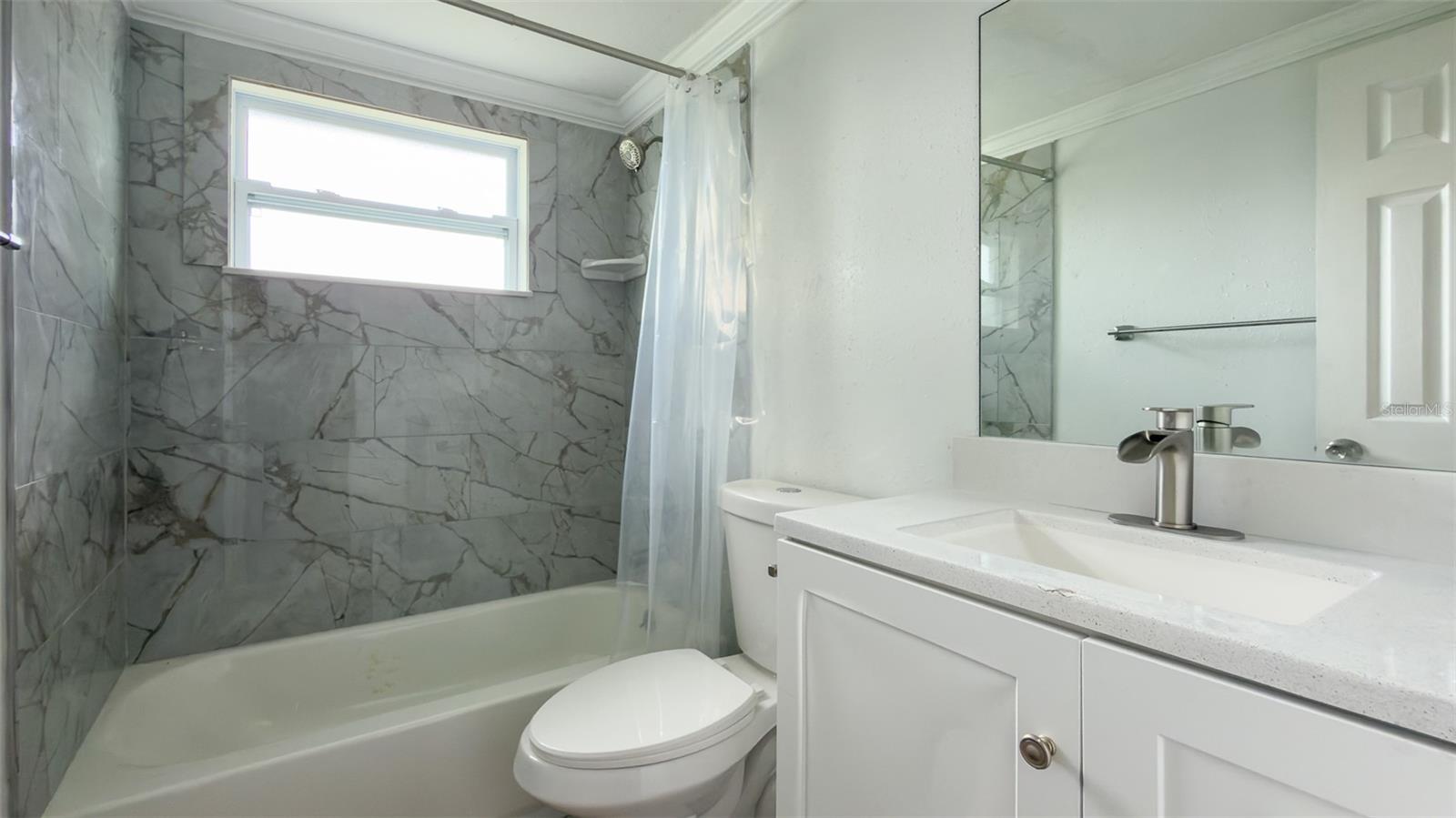 Updated bathroom featuring marble-look tile and a modern quartz vanity.