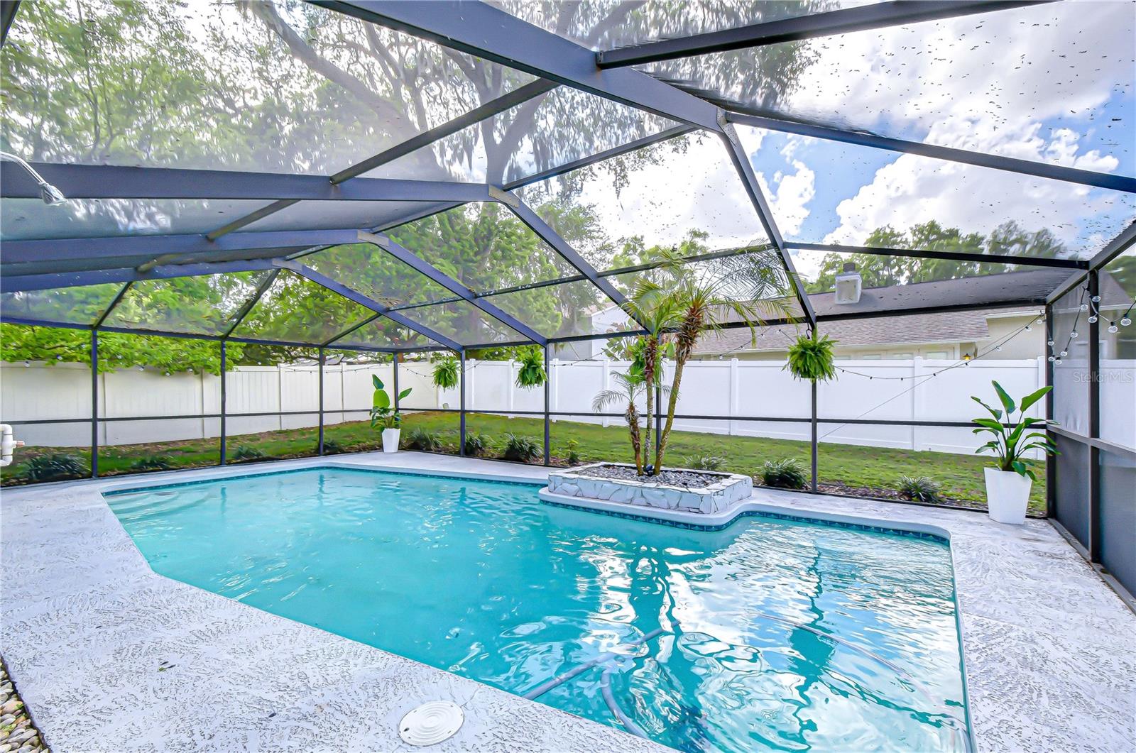 Pool with view of mature oak trees and lush greenery.