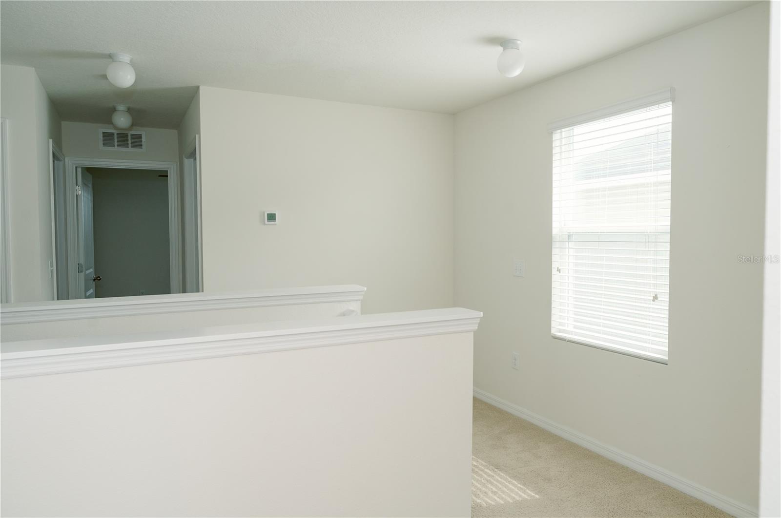View from upper stairway landing looking at hallway to 2nd bathroom on left, laundry room on right and bedroom 3 door