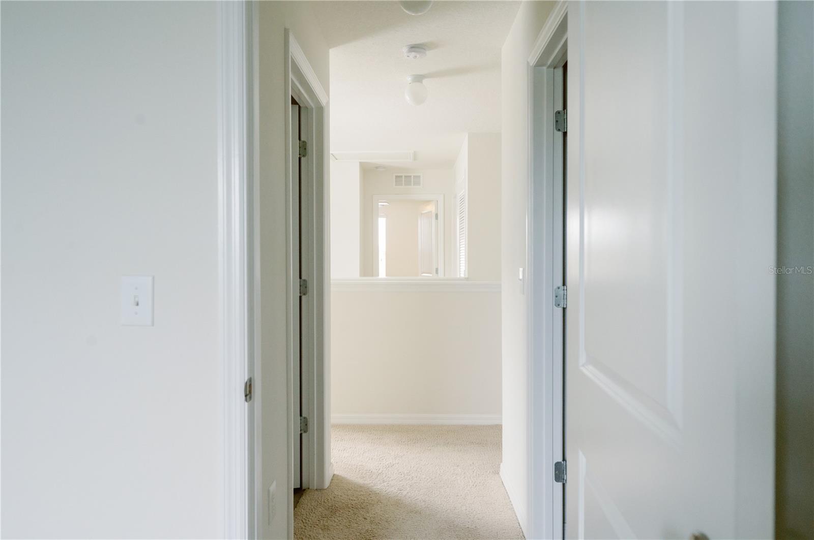 View from doorway of bedroom 3 across upper stairway landing towards bedroom 1 (right) and bedroom 2 (left)