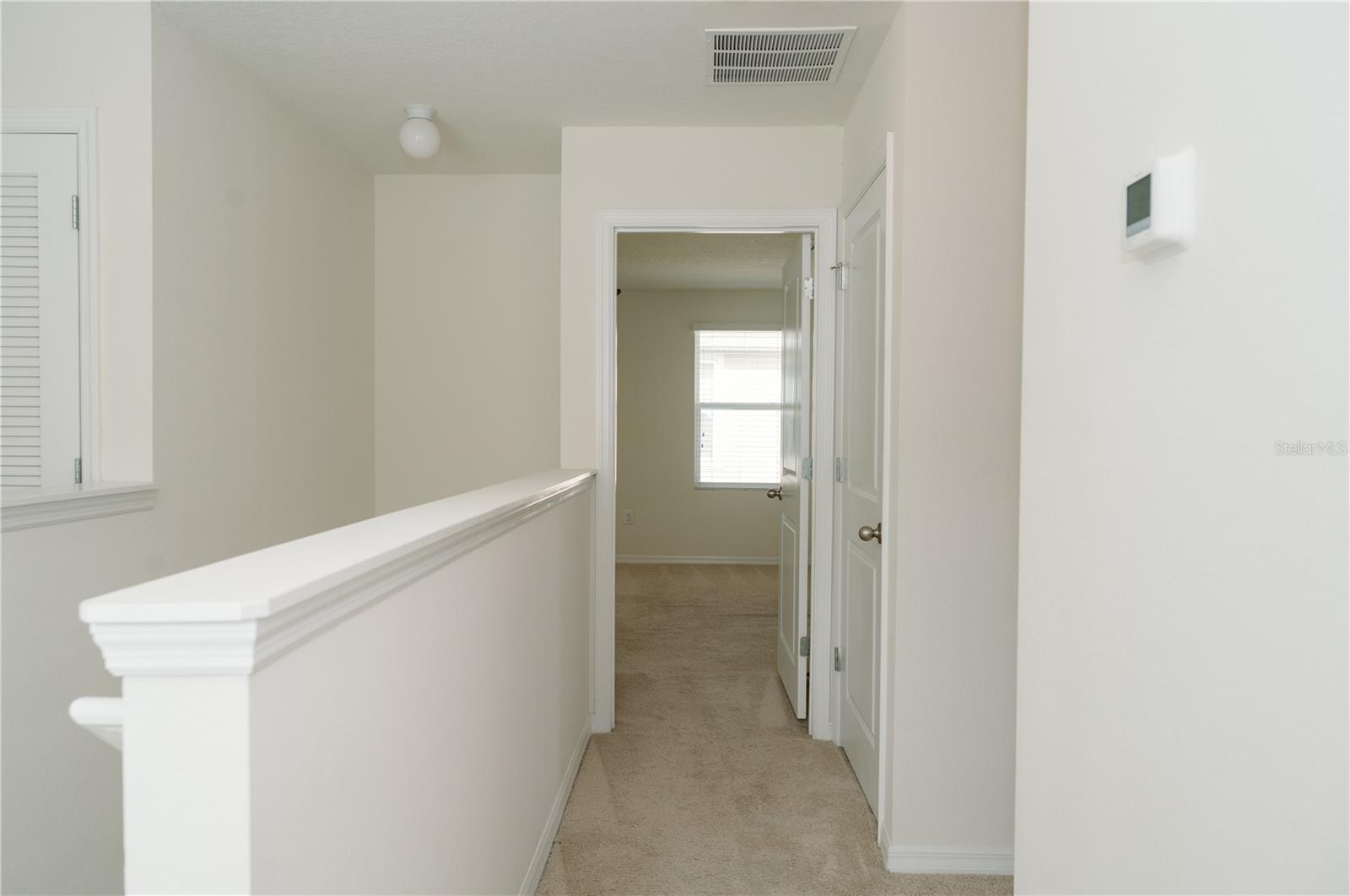View from upper stairway landing looking towards the primary bedroom door and the hallway (right) to bathrrom, lanudry room and bedroom 3