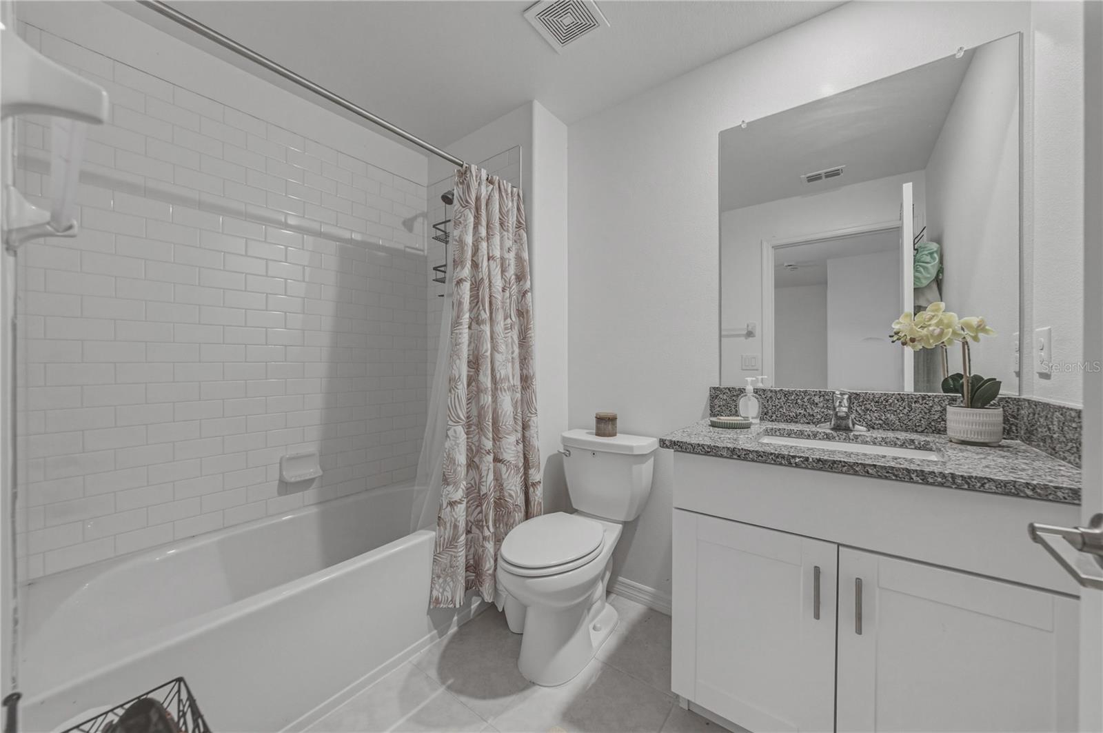 Full Second Bedroom Upstairs with Tile Surround, Square Undermount Sink and Granite Countertops.