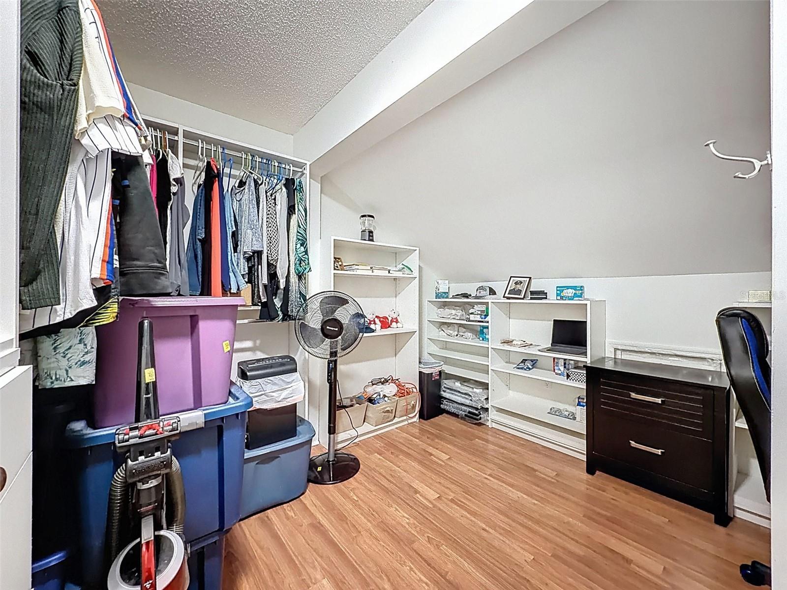 Extra room in primary suite as walk in closet with customized shelving or office space or extra storage use.