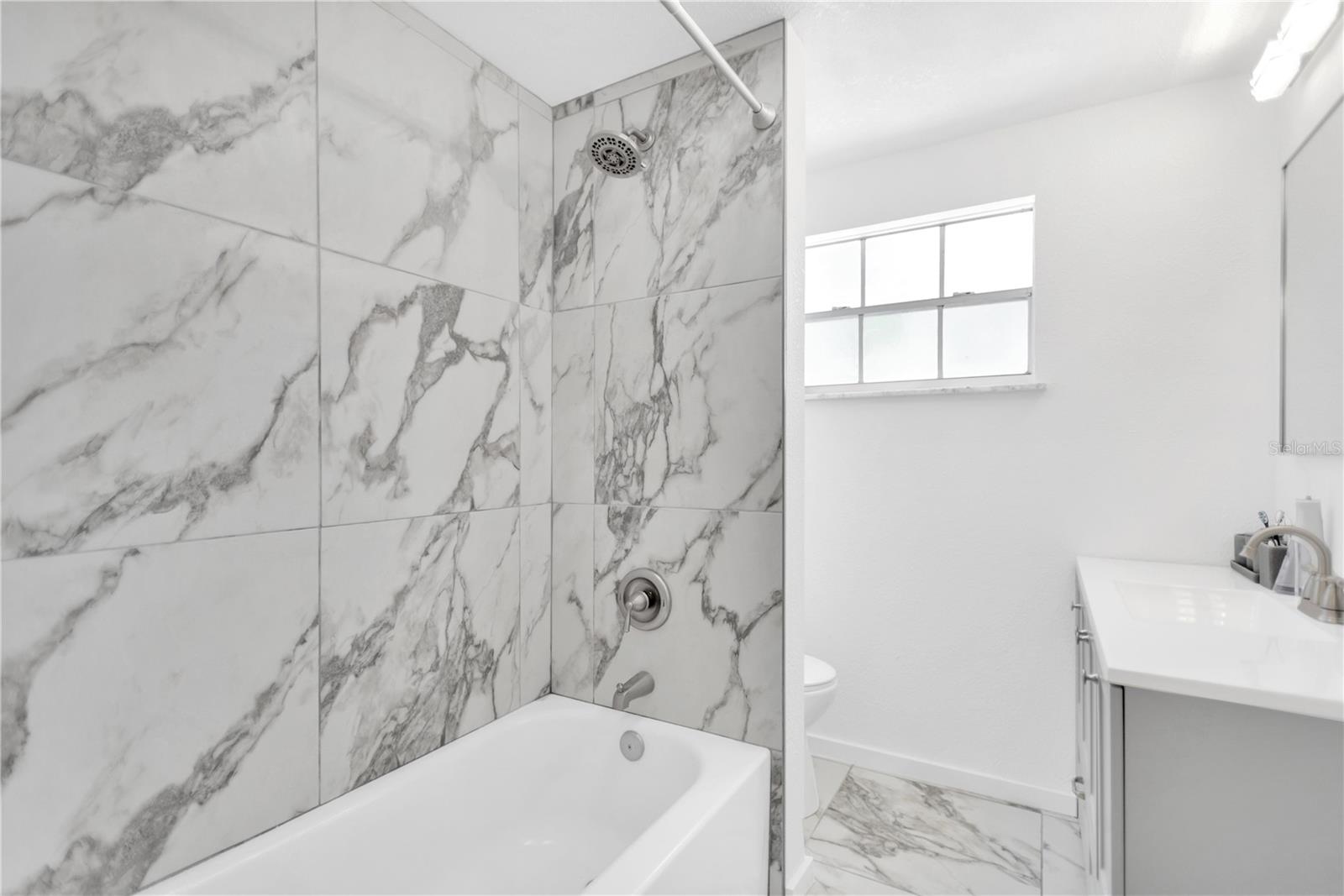 Guest bathroom offers shower with tub carrying the elegance of full tile forward.