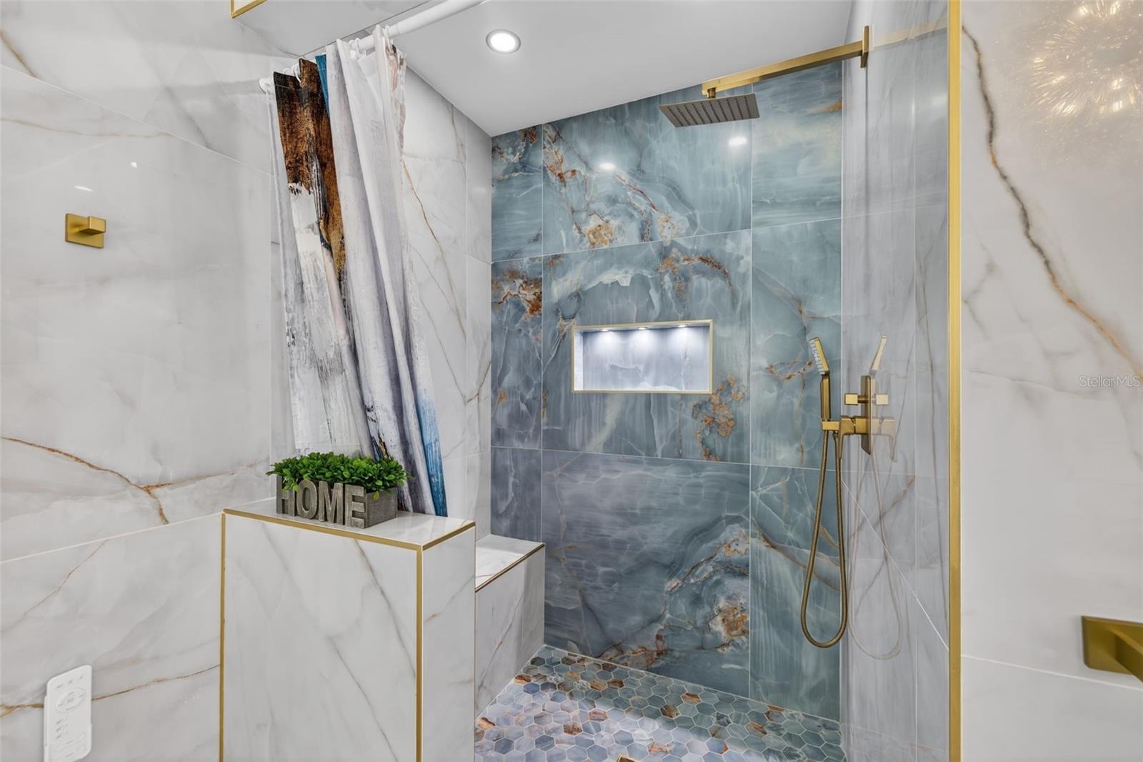 Master bathroom features walk-in shower with recessed lighting, built in bench, and light-up shelf.