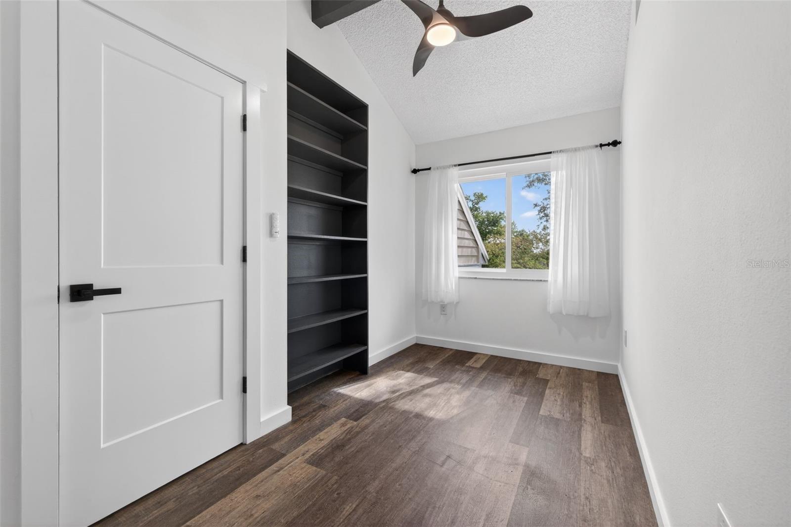 The master bedroom has a space for a sitting area or office, built-in shelving, and a separate ceiling fan.