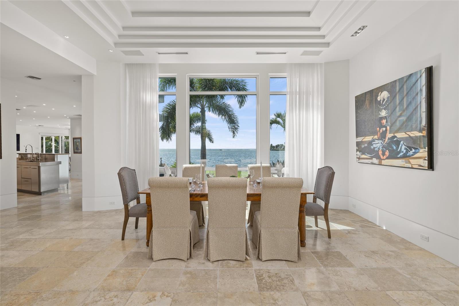 Elegant dining room with coffered ceilings, waterfront views, and natural light