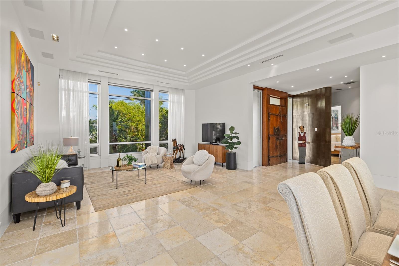 Light-filled living room with tray ceilings, modern seating, and garden views