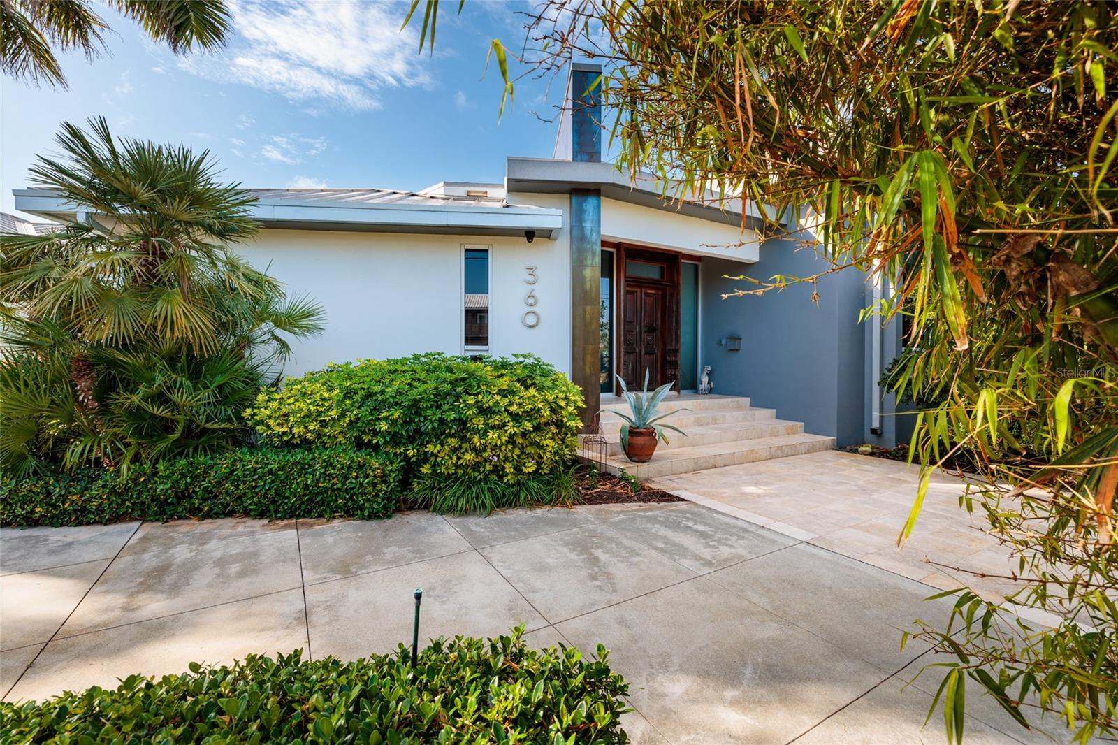 Striking modern front elevation framed by lush tropical landscaping