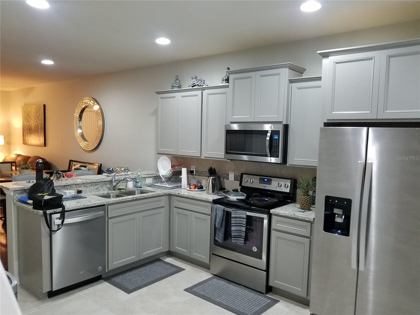 Stylish open kitchen with granite counters, stainless steel appliances, and breakfast bar overlooking the living area—ideal for entertaining and enjoying the home’s inviting, connected layout.