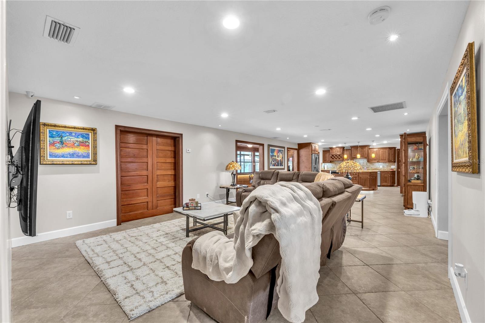 Solid sliding barn doors separate the living room from the florida room along the back of the home.