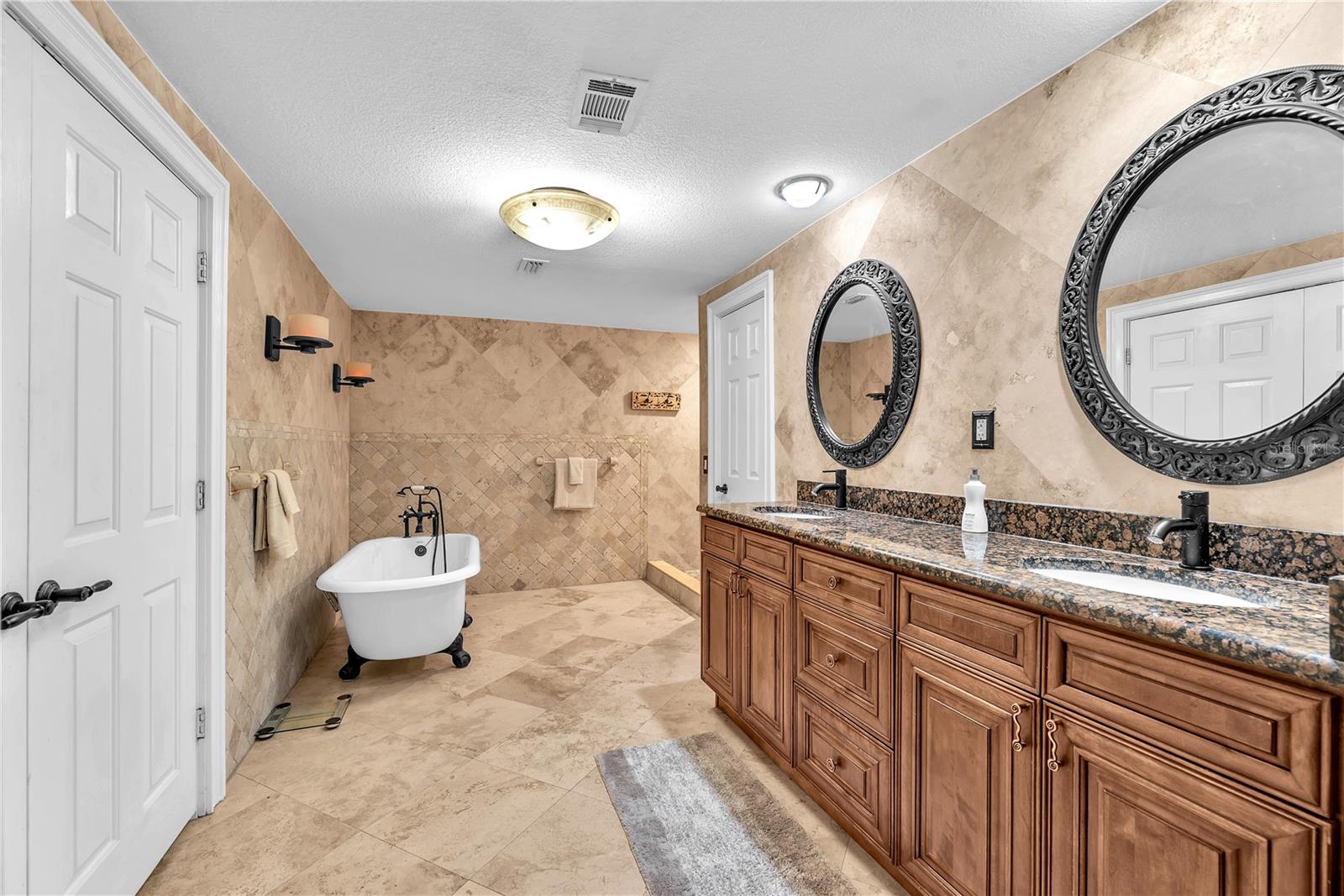 The spa-inspired primary bath has a stunning vanity with dual sinks, a claw-foot tub, separate shower and water closet and a washer and dryer tucked behind the double closet doors.