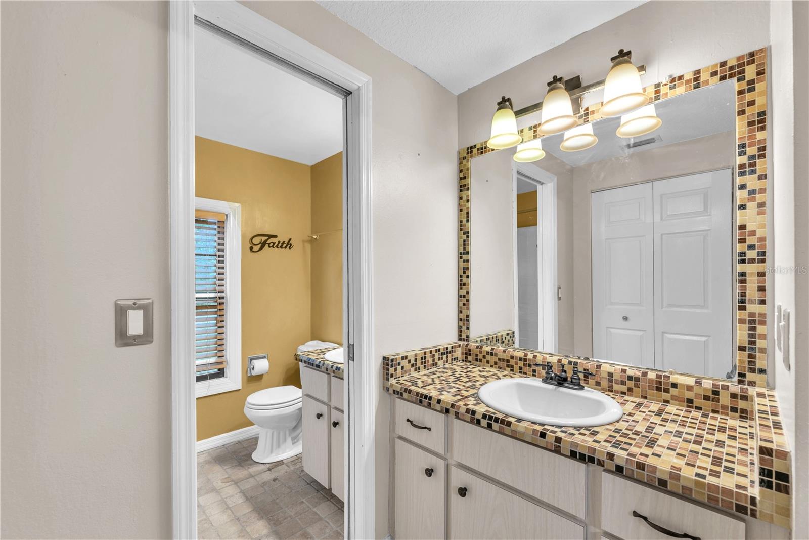 Second vanity and storage closet seperated with a pocket door outside of full bathroom with tub/shower combination.