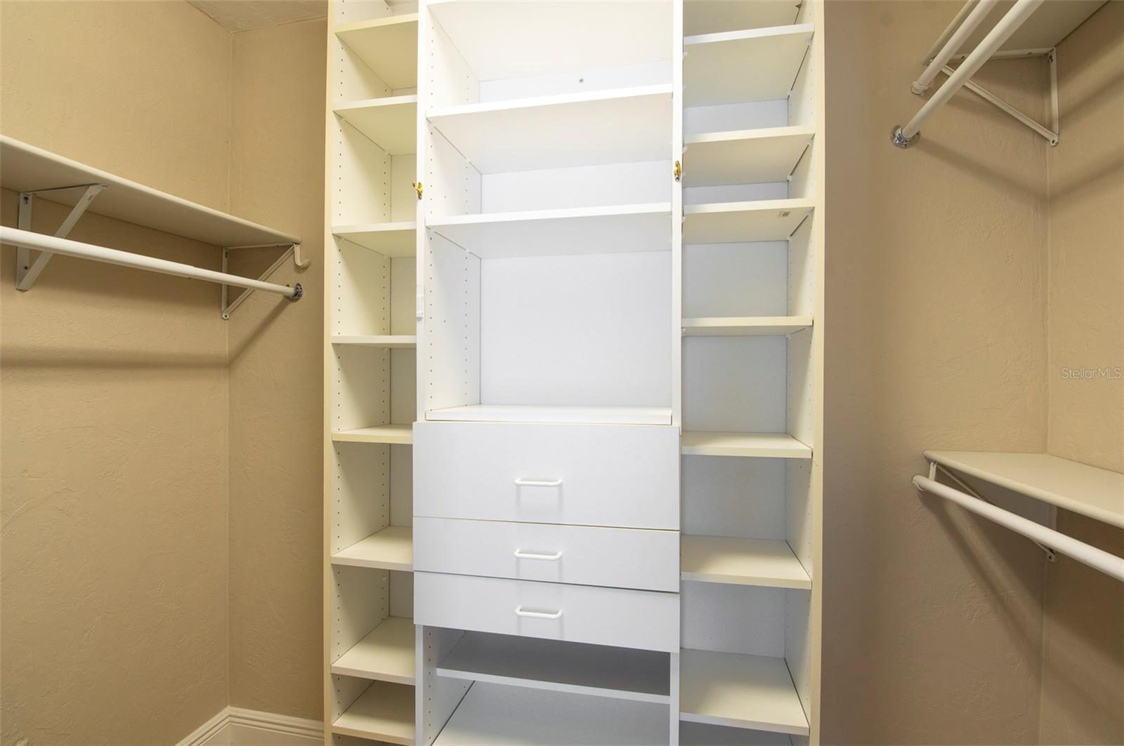 Primary bedroom walk in closet with mirror doors