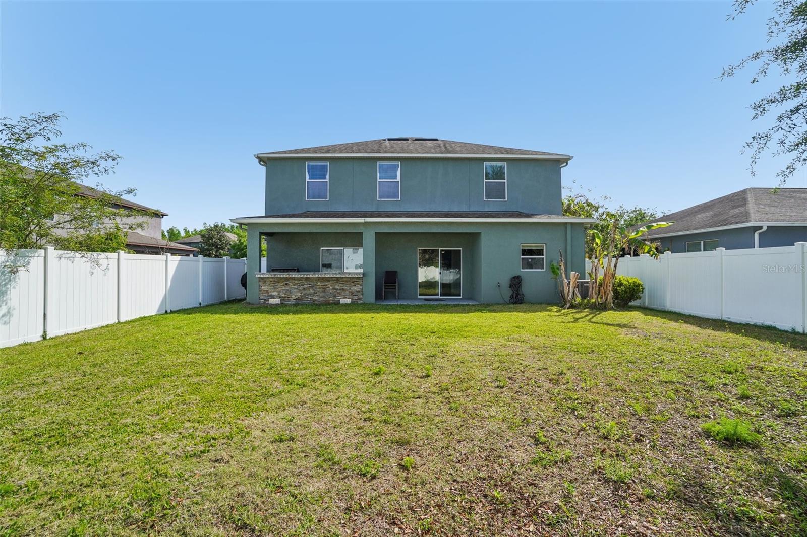 Backyard - The rear elevation showcases the home's covered patio, built-in outdoor kitchen, sliding glass door access, and expansive fully fenced backyard — a seamless blend of indoor and outdoor living.