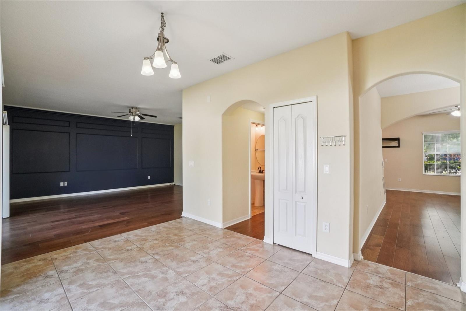 Open breakfast nook area off kitchen with large-format tile flooring, pendant light, and views into family room and adjoining living spaces.