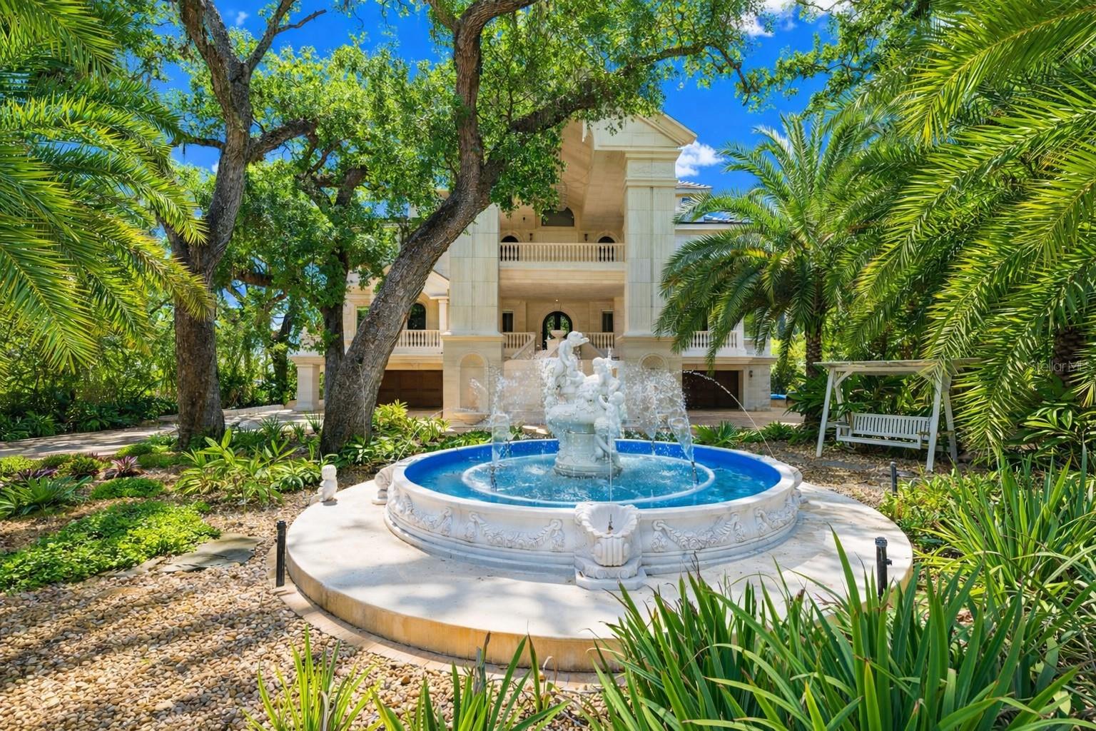 Gated estate entry with grand motor court and fountain arrival.