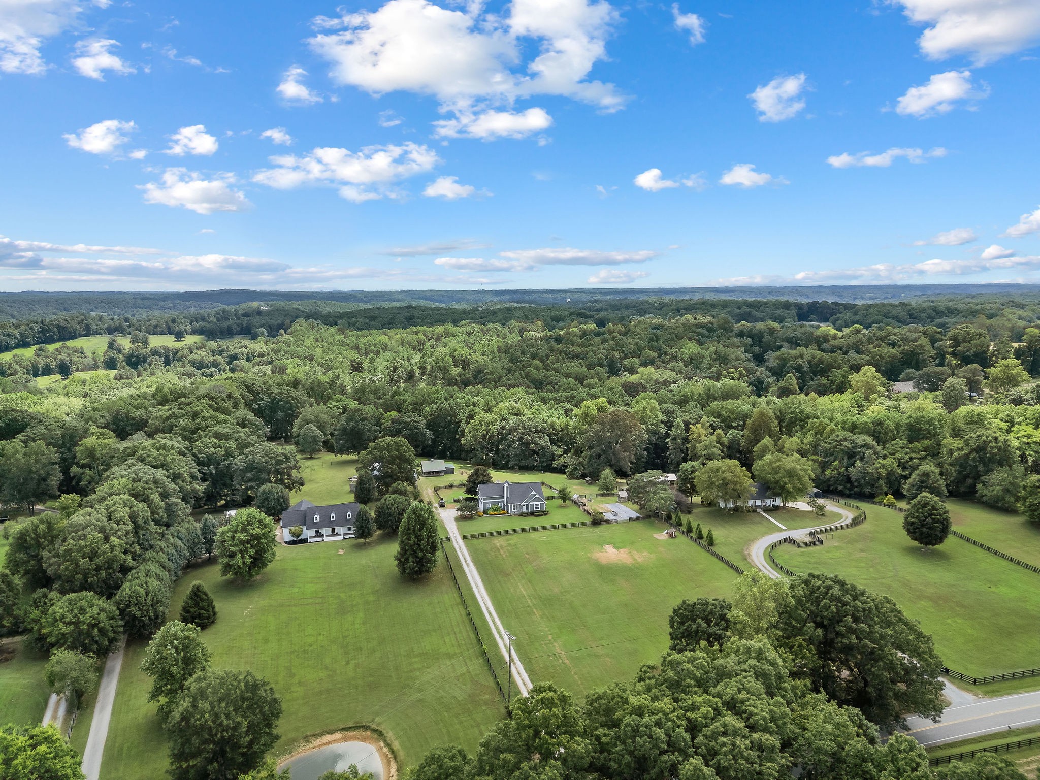 Another aerial shows the barn behind the home, separated from the home by the fence yard and small pasture. Barn has a tack rm/office, loft, two animal stalls and covered wood storage!