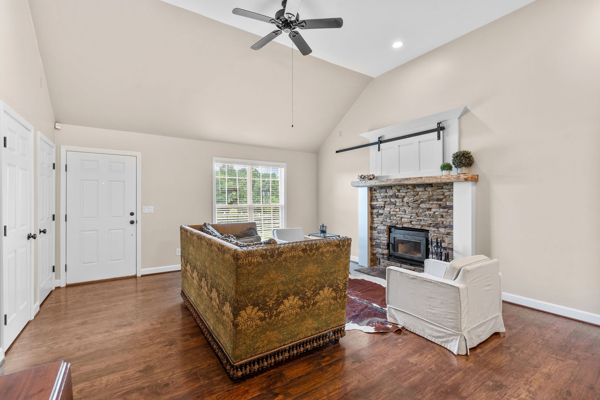Another view of the living area shows the large window overlooking the front of the property, two storage closets to the left, high-efficiency wood-burning fireplace and the small sliding barn door concealing the flat screen television.