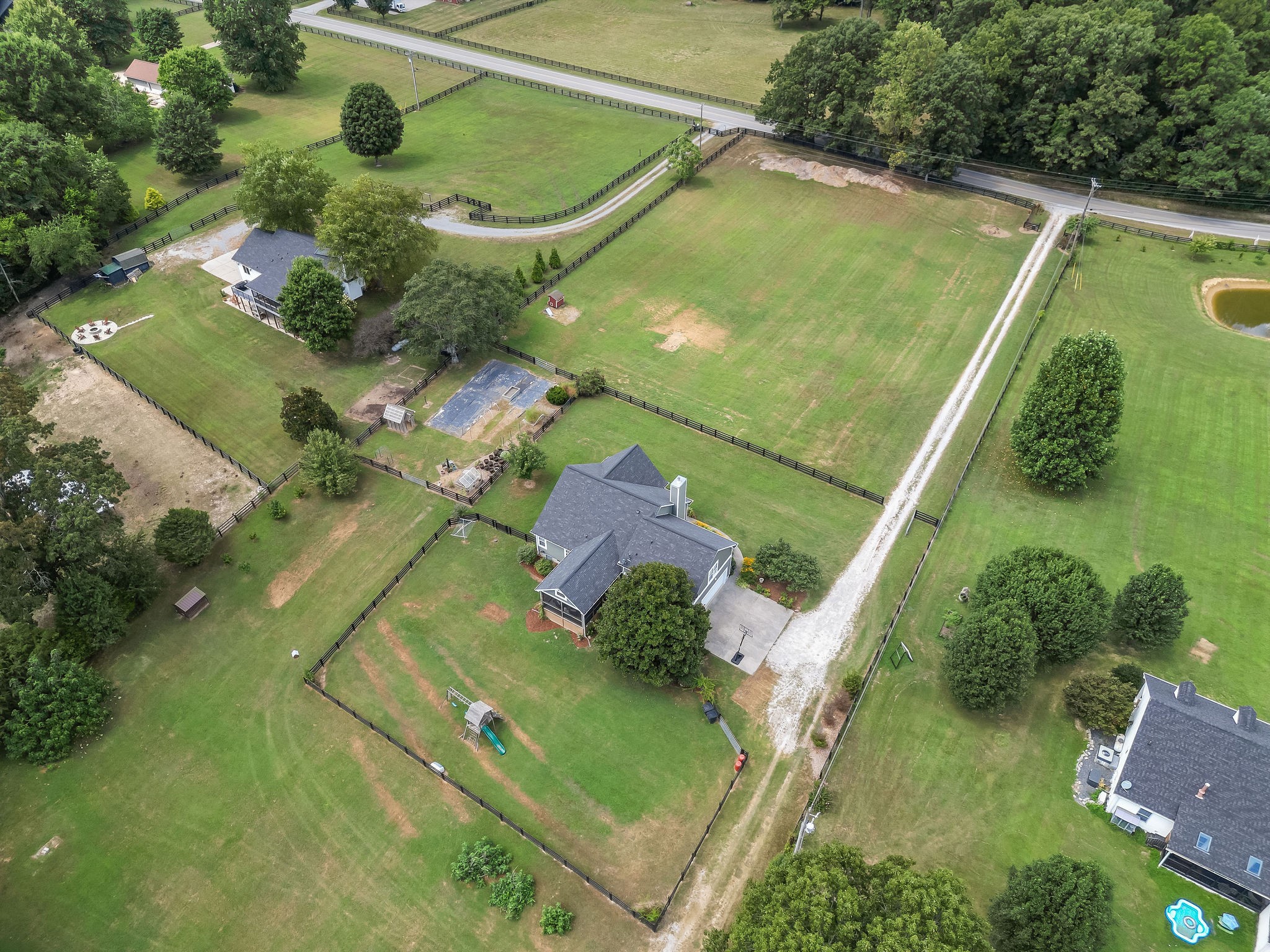 A view from the left rear corner of the fenced back yard shows the large fenced/gated pasture to the front of the house. The large magnolia tree growing near the house provides shade for the huge outdoor screened room & yard. The smell of the blooms