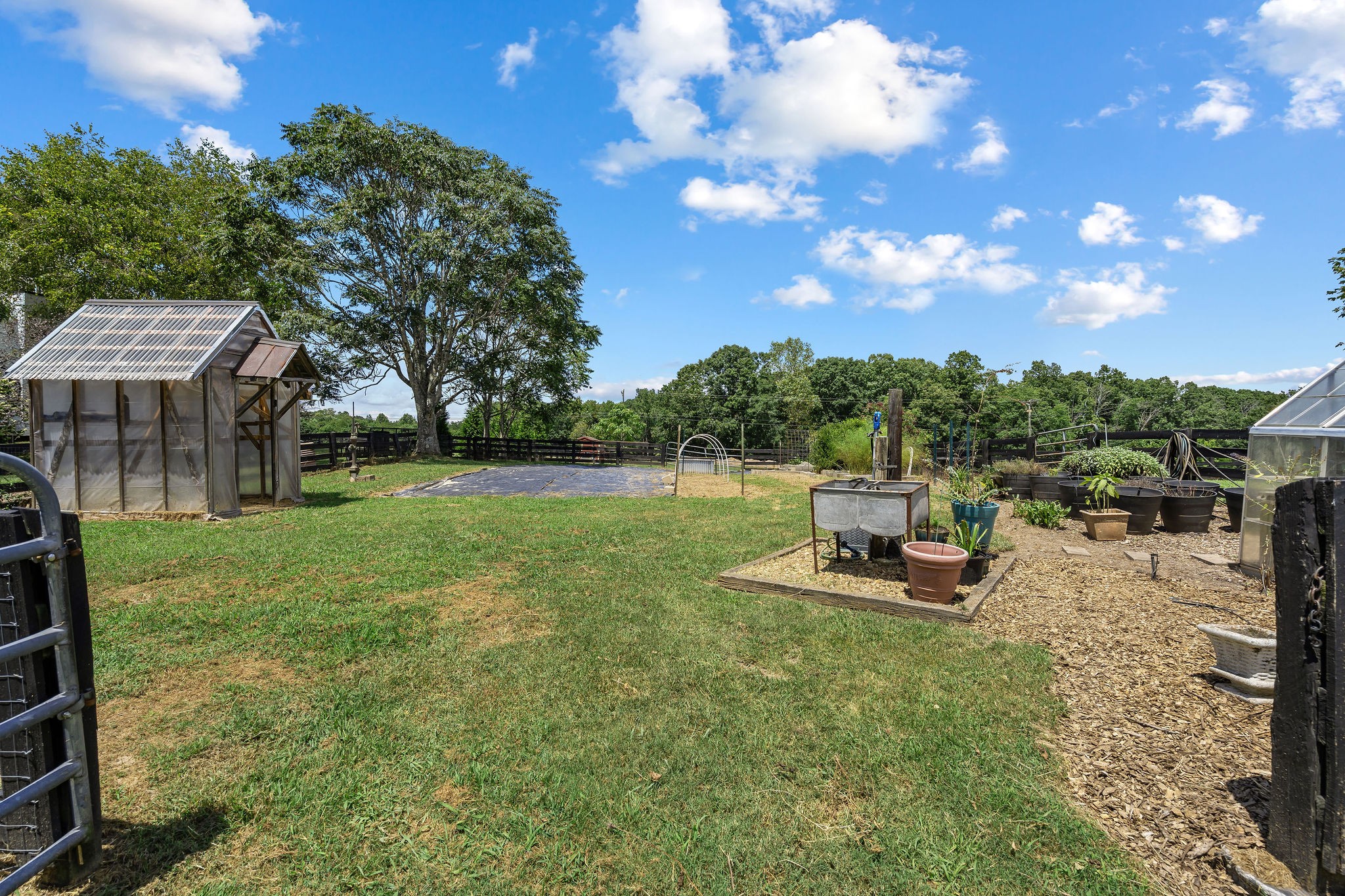 The garden is between seasons now and has been covered to help keep it weed-free for the new owners. One of the two small green houses can be seen to the left.