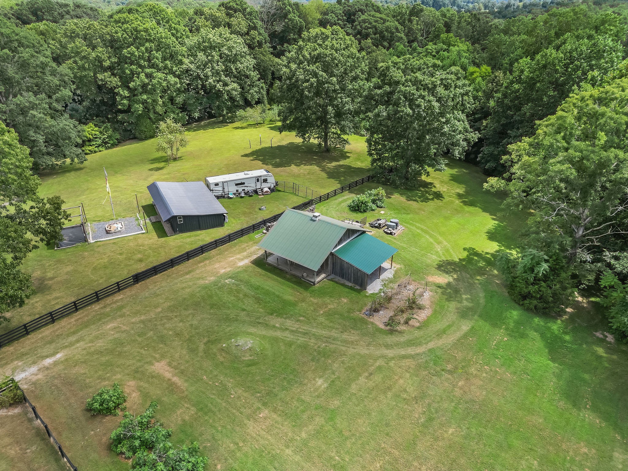 The home barn features a tech room/office with electric electricity, a landline, phone, a wall, air conditioner, two animals stalls, loafed, and covered firewood storage. Fig trees are seen at the bottom left in the photo and behind the barn.
