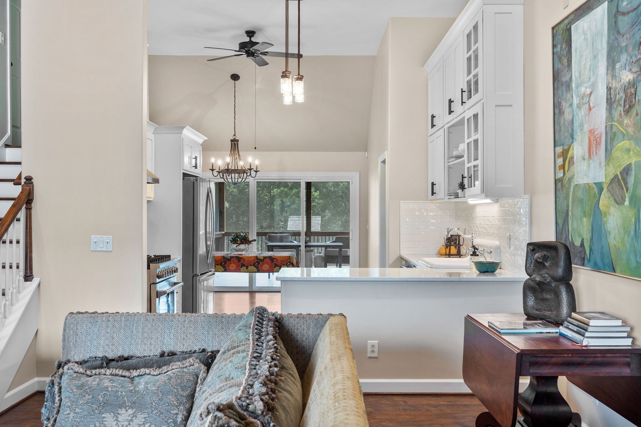 The open concept floor plan flows from the living room to the kitchen, and to the dining area and the screened room beyond the sliding glass wall.