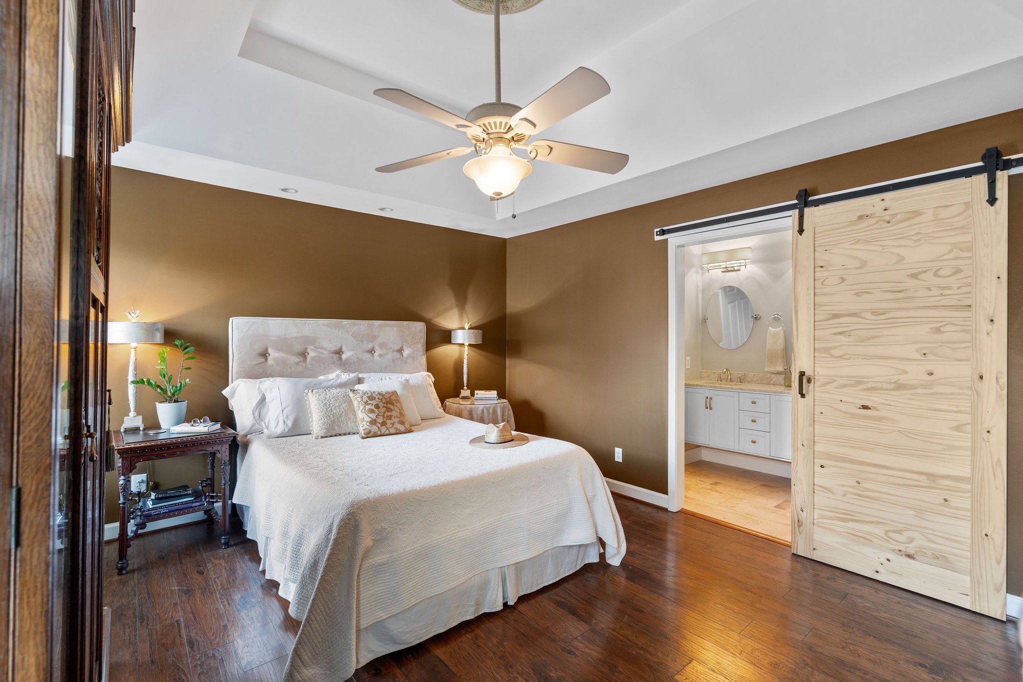 The roomy primary bedroom of this homestead has a sliding barn door leading into the bedrooms, private floor bath.