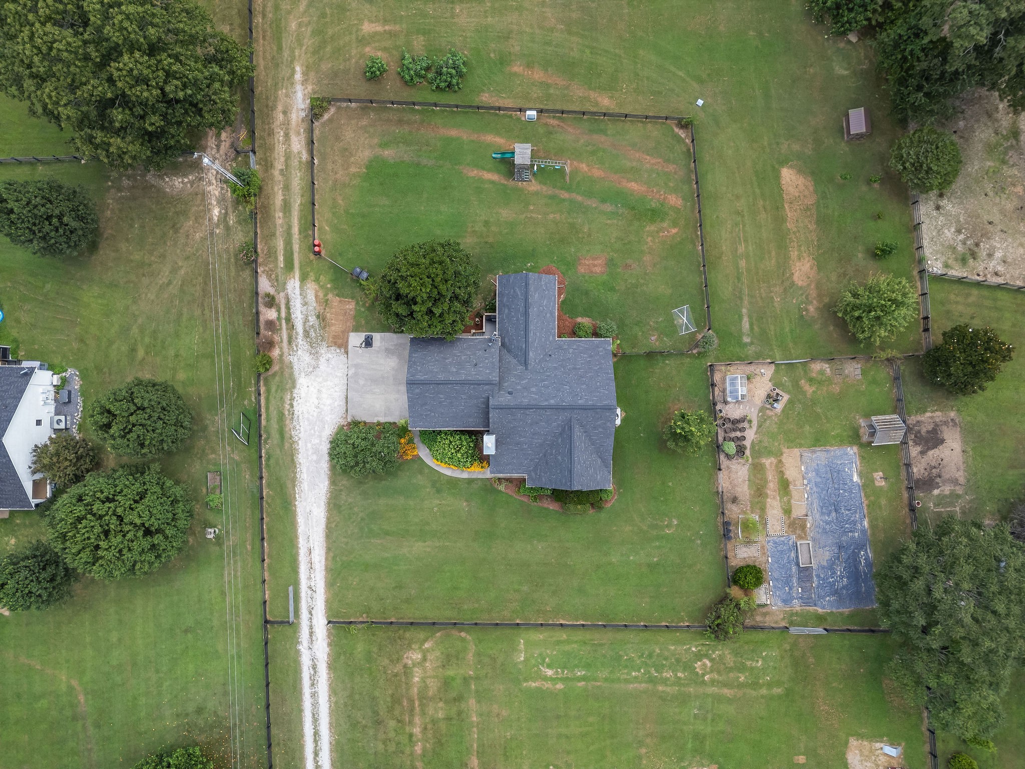 The layout around the house shows the fenced front and back yards, and the fenced garden area to the right of the house with two small green houses. The property’s wellhead is located in the garden area and has a cast iron hand pump installed on it.