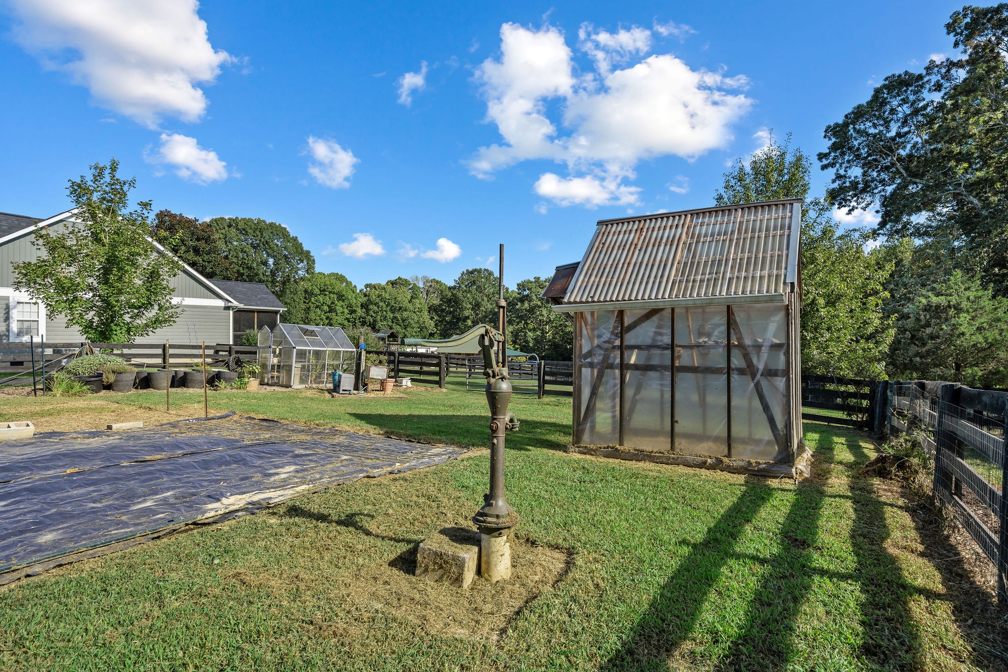 The wellhead is capped by a cast-iron hand pump with a hose hook up, so it can service the garden if needed. The water faucet for the garden area located near the greenhouse in the center of the photo.