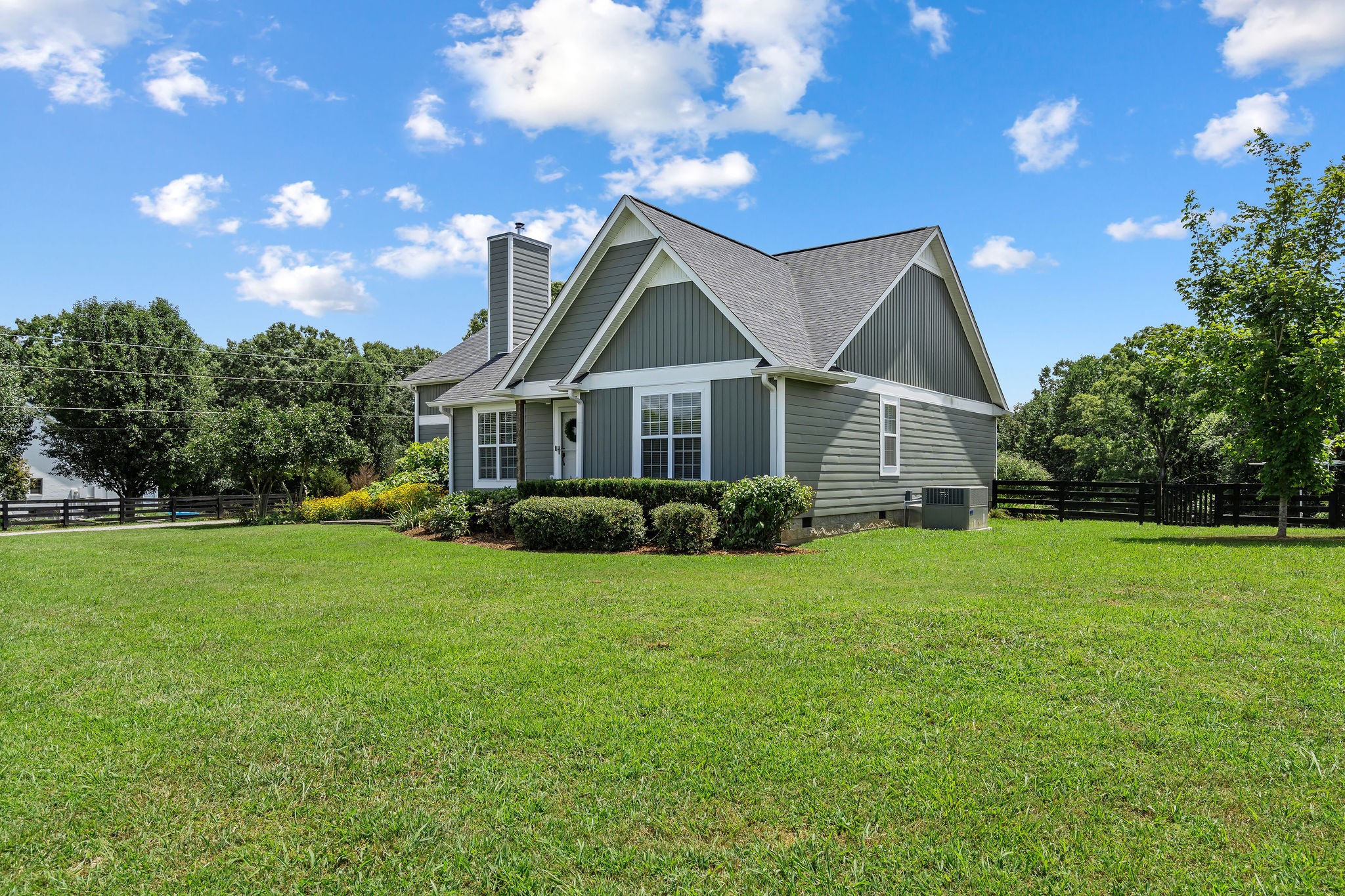 A view from the right side of the house shows the fenced backyard. The fenced garden area with two greenhouses is just to the right in this photo.