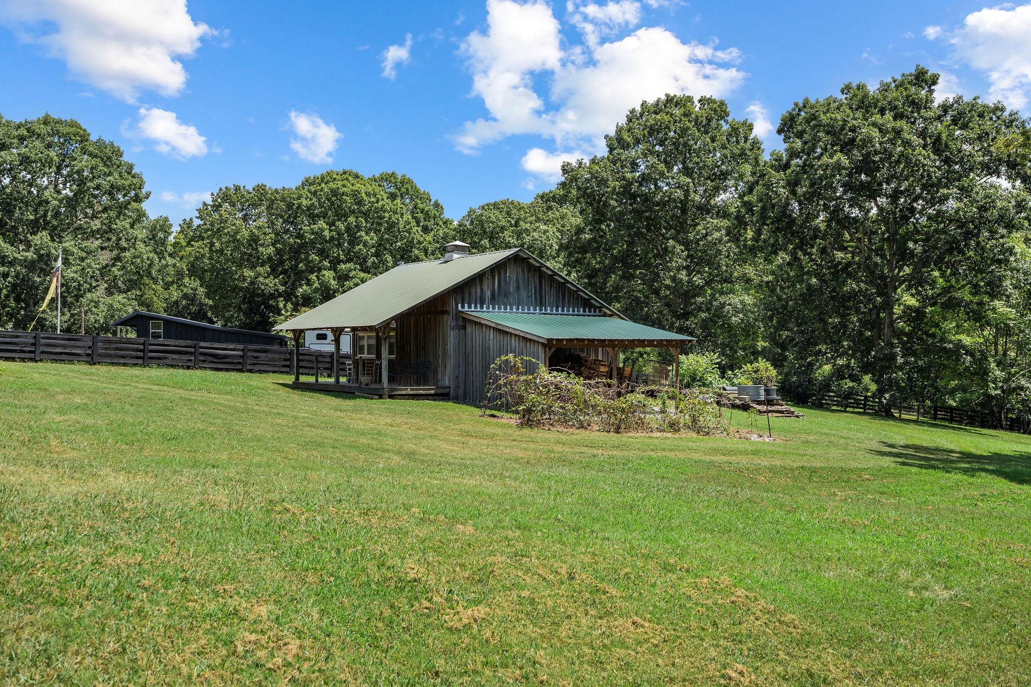 This view of the barn shows the covered firewood storage area on the right side of the barn. The property continues behind the barn and into the woods where there is a spring-fed creek.