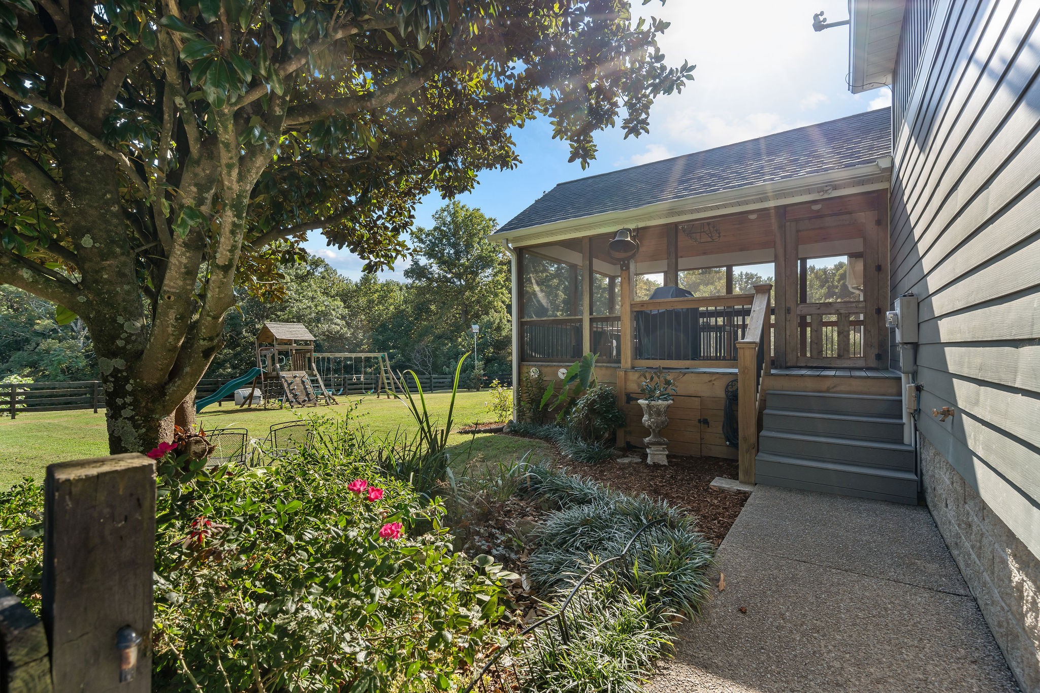 The walkway to the screened outdoor room opens up to the fenced backyard