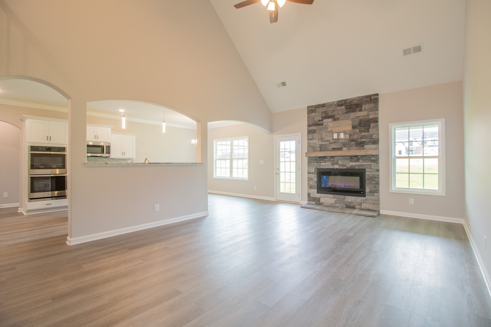 Spacious Living Room with a Stone Fireplace, Floating Wood Mantle, 2 Story Ceiling and Access to the Large Patio!
