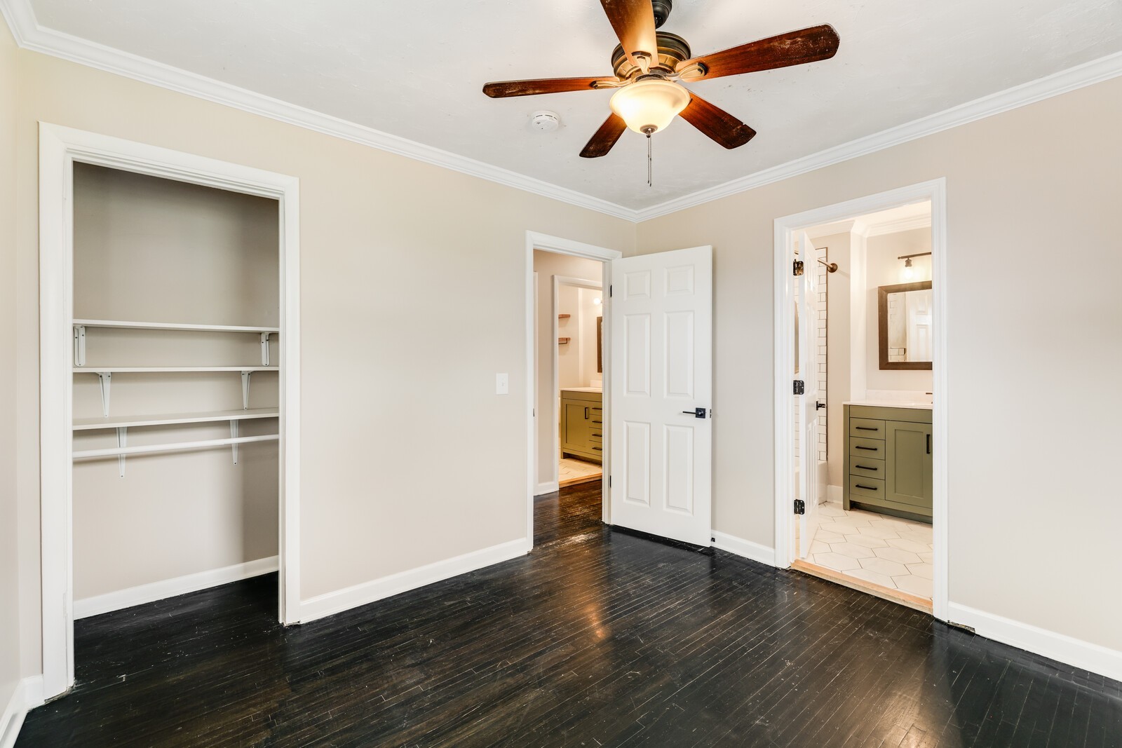 The primary bedroom with ceiling fan, hardwood floors and updated en suite bathroom
