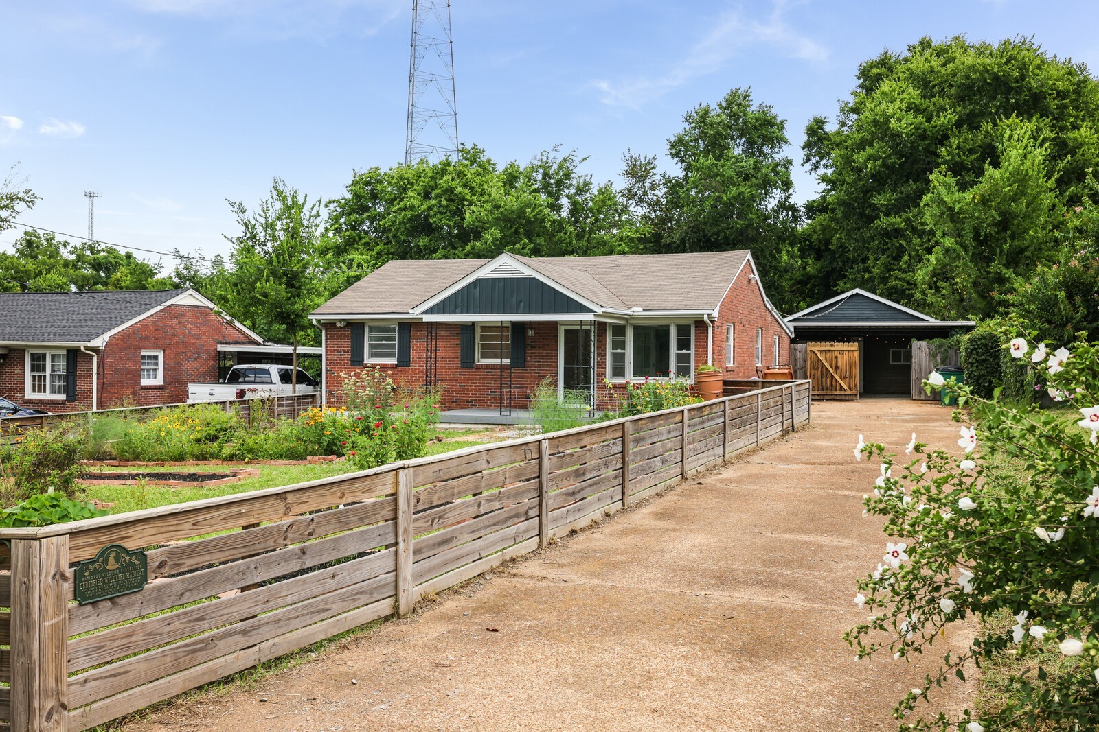 A fenced front yard with raised flower and vegetable gardens greets you as you drive up the ample driveway
