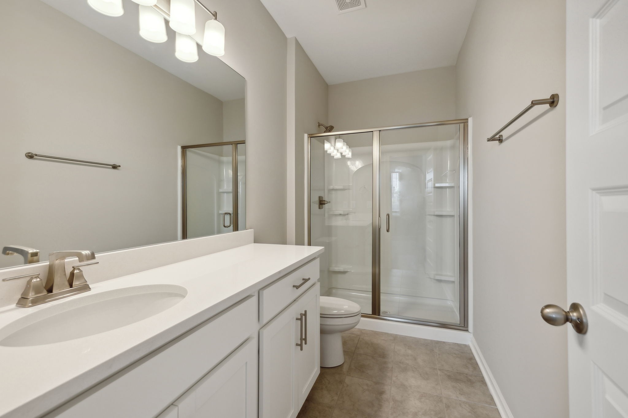 Primary Bath is Equipped with Double Vanities (not pictured), 5' Shower Insert with Glass Door, and Beautiful Ceramic Tile.