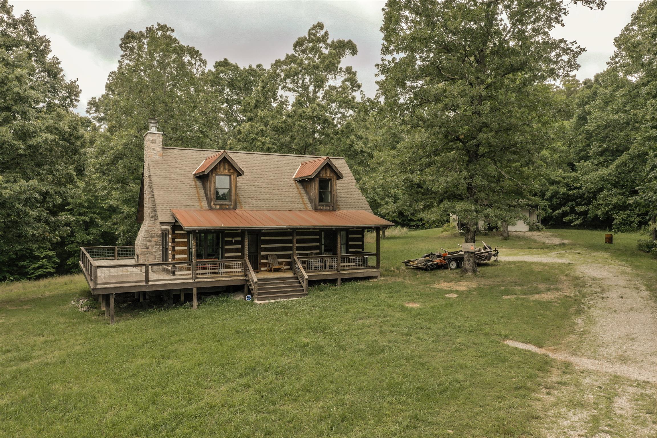 7327 Brush Creek Rd Fairview, Tennessee Gatlinburg style setting in Williamson county..Perfect songwriters retreat...2016 cabin nestled in very peaceful and serene setting on 30 acres with a detached garage. This charming cabin boasts many modern features such as open floor plan, tin ceilings, indoor and outdoor fireplaces, wraparound porch and much more. Enjoy the abundant wildlife, springs, and creeks. Seller including most furniture and Kabota tractor with bush hog and finish mower.