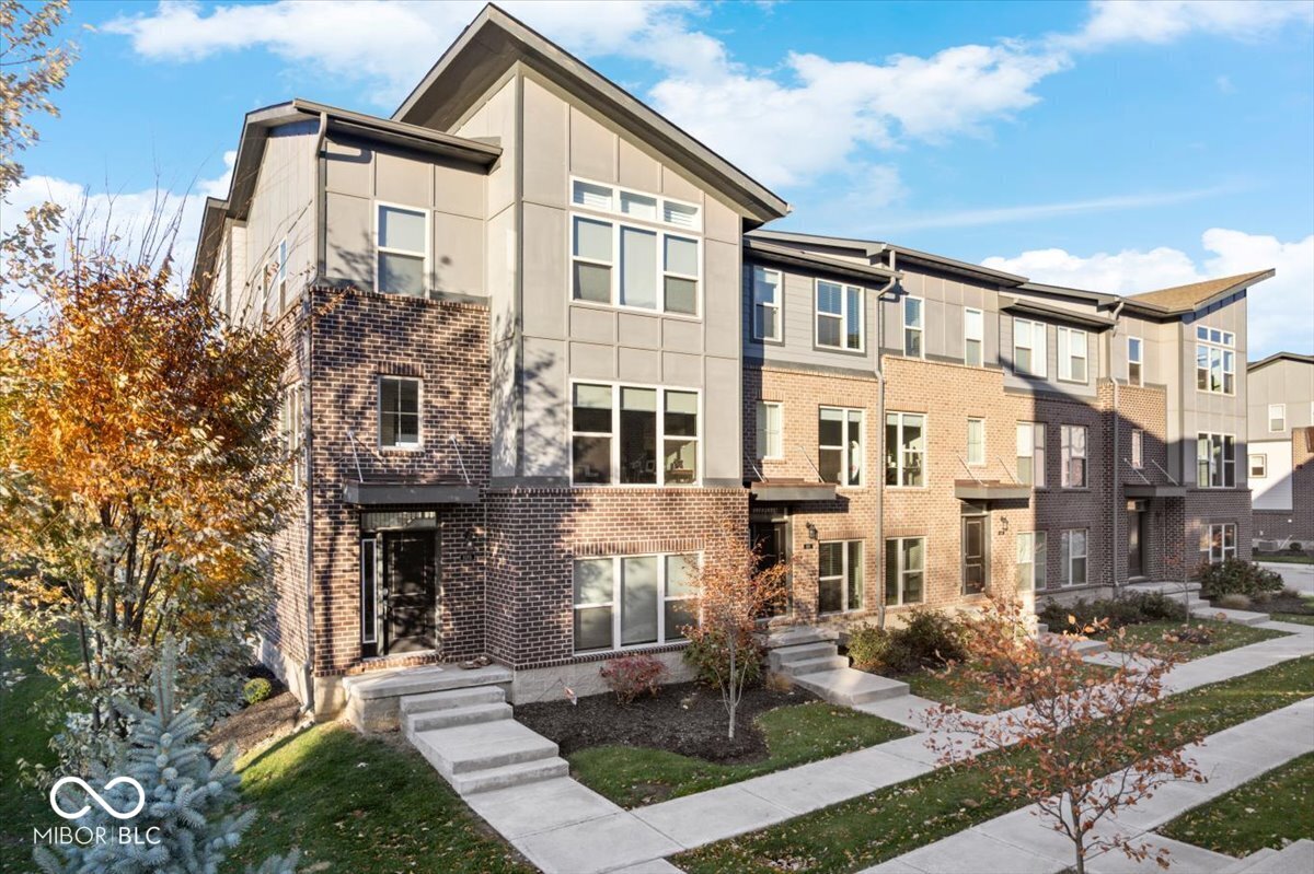 Step into modern luxury in the heart of walkable downtown Fishers-one of the fastest-growing, most sought-after communities in the country. Built in 2020 and meticulously maintained, this stunning townhome offers the lifestyle everyone is talking about. Just steps from vibrant restaurants, boutique shops, the Nickel Plate Trail, and all the energy of a booming, dynamic downtown, this is truly urban-suburban living at its finest.    From the moment you enter, the soaring two-story foyer and incredible natural light set the tone. Expansive windows frame every level, creating a bright, uplifting atmosphere throughout. The lower-level bonus space is a dream-perfect as a media room, game space, gym, or the ultimate work-from-home office. On the main level, enjoy a flexible living/dining area that adapts effortlessly to your lifestyle.    The open great room is the heart of the home, centered around a striking gas fireplace and seamless flow into the chef-inspired kitchen. Quartz island, sleek cabinetry, stainless appliances, and direct access to your private deck overlooking a peaceful wooded backdrop-an ideal space for morning coffee or evening grilling.    Upstairs, the vaulted primary suite feels like a retreat with oversized windows, a massive tile walk-in shower, dual sinks, private water closet, and a generous walk-in closet. Two additional spacious bedrooms and a full bath offer versatility for guests, hobbies, or another office. A convenient upper-level laundry room adds to the ease of everyday living.    The finished garage with newly sealed floors is the cherry on top-truly move-in ready from day one.    If you're looking for modern design, unbeatable walkability, and an elevated lifestyle in one of Indy's most thriving communities, this townhome has it all. Welcome home.