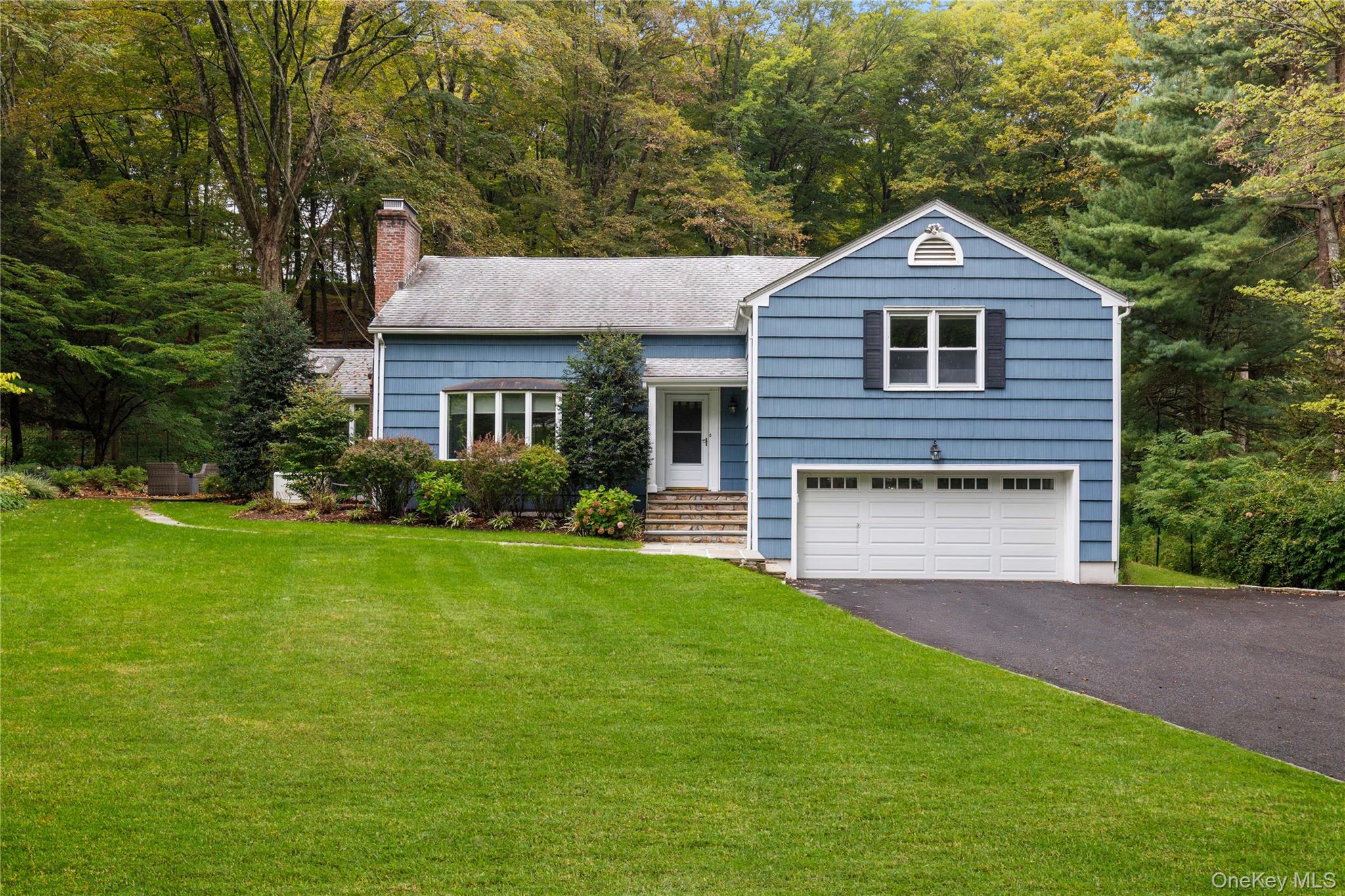 Nestled privately back from the street, this stunning residence offers a seamless blend of indoor elegance and outdoor serenity. The heart of the home is an airy, open-concept first floor anchored by a cozy wood-burning fireplace and a renovated chef’s kitchen. This level flows naturally into a bright family room with exposures on three sides. This level also opens through sliders to an expansive entertaining deck. For quieter moments, a secluded bluestone side patio provides a peaceful escape. The unique side split-level design is tailored for modern lifestyles. Just a half-flight up, you’ll find a restful primary suite and a second bedroom. One more short set of stairs leads to a massive third bedroom with a private bath—a versatile "mega-suite" that easily doubles as a quiet professional workspace or guest wing. Completing the home is a finished walk-out lower level, offering the perfect flexible space for a home gym, media room, or play area, with direct access to the two-car garage. With its blend of private outdoor extensions and dedicated living areas, this home perfectly adapts to your every need. Did we mention the automatic generator? Welcome home!