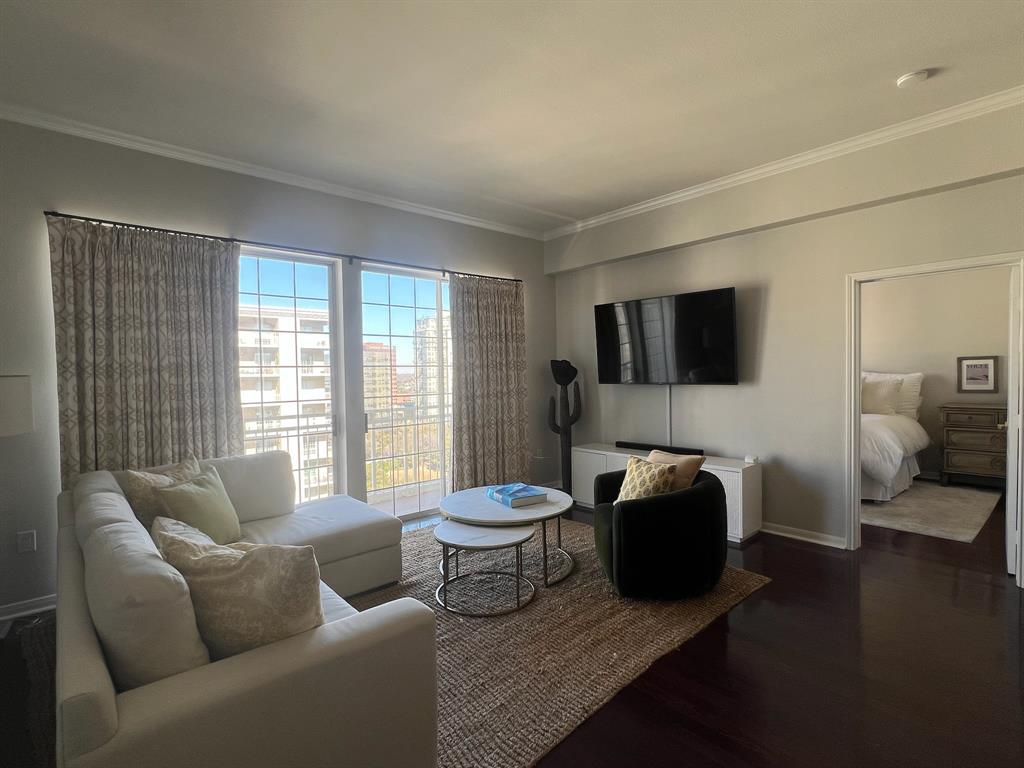 Living area with crown molding and dark wood-style floors