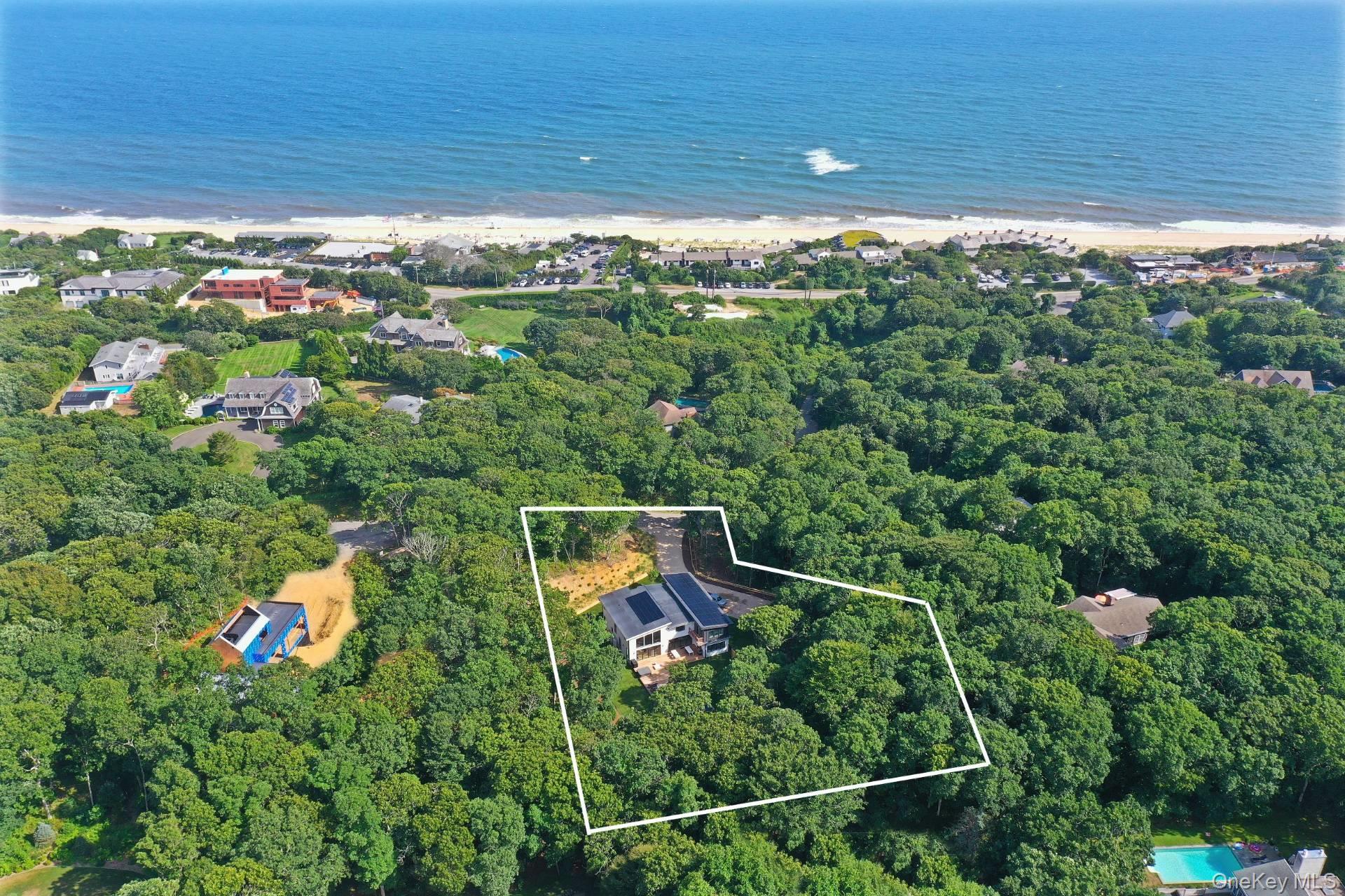 Set in the privacy of Hither Woods, this six bedroom, four and a half bathroom offers contemporary sophistication while staying true to the open and free and environmentally friendly spirit of Montauk. The 5,155 sq. ft. two story home has it all with its 28,000 watt roof mounted solar panels, and high efficiency HVAC. Each room has it's own individually controlled zone thermostat for maxim comfort and the house has Low E Anderson windows with heat lock coatings for maximum energy performance whether enjoying this home in summer or winter. Walking through the contemporary styled entrance reveals an open expansive living room with high ceilings, a dining room with a long slate table that seats twelve directly adjacent to a large open, fully appointed, California style kitchen. The living room, dining room and kitchen all have views of the 15x30 pool, hot tub and large yard with excellent privacy. Along the east side of the first floor is a bedroom with an ensuite bathroom leading to the first floor den and access to an extensive, ready to be finished, basement. The second floor features a primary bedroom with a modern roomy bathroom. This floor also features a large guest bedroom with it's own full bathroom. Three remaining bedrooms and another bathroom also adorn the second floor, they all have good storage space, great privacy and views of the amazing area surrounding 19 Elm. Situated near trendy Old Montauk Highway, Gurneys Inn and Hither Hills State Park, 19 Elm captures the classic, open and free spirit of Montauk in a contemporary, modern home.