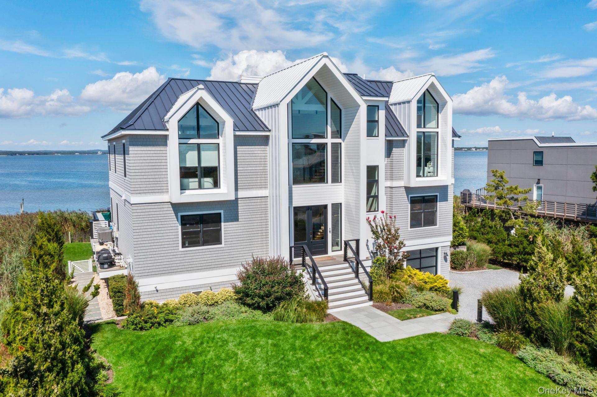 Discover Coastal Elegance at its Finest in Westhampton Dunes
Sitting gracefully on 105 feet of open bayfront, this stunning residence epitomizes the pinnacle of modern luxury and design. Crafted with meticulous attention to every detail, this 5-year-young home spans 5,200 sq. ft. across three levels of impeccable living space, offering unparalleled views of Moriches Bay.  From the moment you enter the soaring 30-foot foyer, you'll be greeted by an open, sunlit layout that blends coastal charm with sophisticated modernism. The spacious living room features a gas fireplace and walls of oversized glass doors, seamlessly merging the indoor spaces with the bay views beyond. A chef's kitchen, outfitted with Thermador appliances and an integrated Gaggenau cooktop with Teppanyaki griddle, offers the perfect setting for culinary creativity. Dual ovens and dishwashers ensure that every entertaining occasion is met with ease, while radiant-heated tile floors on the first level add an extra layer of comfort and luxury. In addition, a media room/den provides a cozy retreat for movie nights or relaxing.  All six ensuite bedrooms, with water views, are designed with privacy and relaxation in mind, providing perfect retreats for all. The primary suite is an oasis of tranquility with panoramic views of the bay, a private balcony, and a spa-like bath. Step outside to your own private paradise. The expansive waterside deck is ideal for both entertaining and relaxing, complete with a built-in BBQ and refrigerator for alfresco dining. The heated Gunite saltwater infinity pool, with a built-in spa, is positioned to take full advantage of the sweeping water views. A 156-foot catwalk, with a 12-foot ramp, leads to the brand-new 2025 floating dock. The home offers a seamless flow of indoor and outdoor spaces, making it ideal for both casual living and grand-scale entertaining. The attached 2.5-car garage and fenced backyard offer ample space for both storage and pets. Mature landscaping frames the property, offering privacy, while the meticulously maintained grounds ensure low-maintenance living at its finest.   Located in a highly sought-after area, where new construction is rare, this exceptional home provides direct access to Moriches Bay for boating, fishing and all water sports, with the added benefit of ocean access just minutes away.