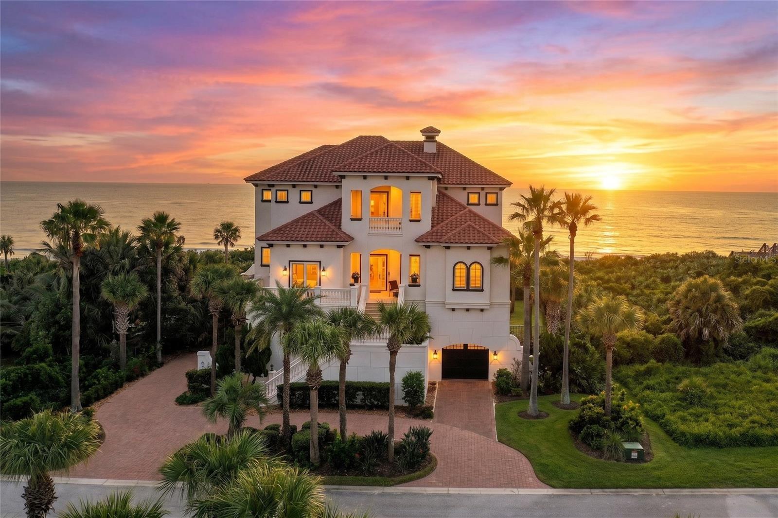 DISCOVER THIS MAGNIFICENT DIRECT OCEANFRONT ESTATE located in the highly desirable "Playa del Sur" neighborhood within the Hammock Dunes Private Oceanfront Community. You'll know you've arrived when you drive down Calle del Sur and are captivated by the impressive collection of homes, with the Atlantic Ocean at the rear and Lake San Gabriel in front.Upon entering the main level, you are greeted by stunning ocean views from every angle. The oversized windows are designed to take full advantage of the exquisite water views from most rooms in the house, as well as incredible sunset views to the west, overlooking the sparkling lake. This main level includes a formal living room with a soaring ceiling and a majestic stone gas fireplace, along with an adjacent bar. The upgraded kitchen features new stainless-steel appliances, including a Kitchen Aid refrigerator, dishwasher, wall oven/microwave, and a commercial-style Wolf 6-burner stove. Granite countertops are found throughout, including in the expansive pantry that also houses one of two washers and dryers.Whether you are sitting at the kitchen countertop, in the breakfast nook, or relaxing in the large family room, all areas offer incredible views, allowing you to spot dolphins swimming, particularly out by the saltwater pool and spa. This dreamy patio also boasts a summer kitchen and convenient access to the pristine beach. Steps lead to a dog run on the side of the house. You'll also find one of the two primary bedroom suites on this level, which features two walk-in closets, double water closets, double sinks, a jetted tub. The beautifully designed dining room, with a tray ceiling, overlooks the lake on the main floor.The ocean views from the second primary bedroom on the upper level are simply amazing and include a sitting area and an oceanfront balcony. There are also east and west balconies on the upper level, plus a richly appointed office. An oceanfront guest bedroom, complete with a full bath and plantation shutters, provides a comfortable retreat for family and guests.The lower level of this home offers numerous possibilities. The garage can hold several cars and is equipped with a car lift for additional space. This level includes a laundry room with a sink and refrigerator, Wine Refrigerator, a fitness room, a bonus room, storage, full and half baths, a theater, and two additional bedrooms. Hammock Dunes is a Private Gated Oceanfront Community with 24-hour Gate Personnel and roaming security plus this home has a fully wired alarm system, including fire, smoke, carbon dioxide and water leaks.In addition to this luxurious seaside lifestyle, membership in the award-winning Hammock Dunes Club is available but not mandatory. The membership grants access to two renowned Audubon-certified 18-hole golf courses, two stunning clubhouses with casual and oceanfront dining, tennis, pickleball, bocce, oceanside croquet, state-of-the-art fitness facilities, an oceanside pool and spa, a splash pad, and a wealth of activities and friendships to last a lifetime. Conveniently located just 3 miles from I-95, this home offers easy access to Daytona, Orlando, Jacksonville, and Flagler Executive Airports.