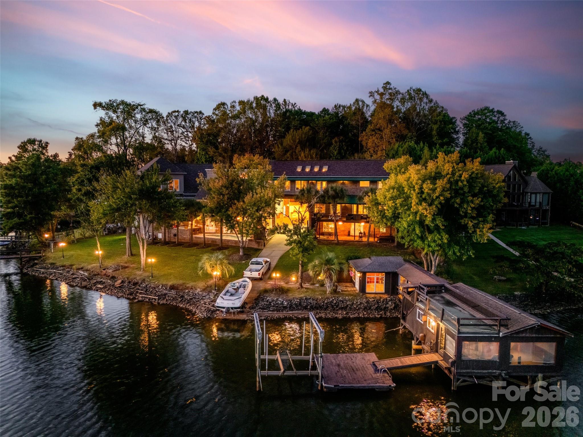 Unique custom-built waterfront home on Lake Wylie, perfect for a large family or those who love to entertain. This exceptional property offers beautiful lake views throughout and includes two private docks (one with a boat lift), a private boat ramp, and a boathouse featuring its own kitchen area. Enjoy the beautiful Gunite pool overlooking the lake and relaxing outdoor fireplace to relax and enjoy.The main residence boasts an open great room with a fireplace, a gourmet kitchen with commercial-grade stainless appliances and a hibachi stovetop, a wet bar, and a walk-in butler’s pantry that leads to a large Trek deck overlooking the water. The primary suite offers vaulted skylights, a private balcony, dual walk-in closets, a fireplace, and a private sitting room with a wet bar. Additionally, the walk-out finished basement includes a separate bedroom and full bathroom leading to a private brick patio.The property also features two distinct wings:- Guest/In-law Suite: Attached to the main home with a private entrance, featuring a large living area, bedroom, bathroom, and full kitchen.- Extended Wing: Includes a custom library/office with a fireplace, theater room, a second great room, a full kitchen, and a bathroom with a sauna. This wing leads to a Gunite pool, outdoor kitchen, and fireplace, as well as a lounge and private theater room.Ample storage is provided by several garages. One garage includes built-in cabinets, while the larger attached garage wing features a 50-AMP RV/camper hookup and extensive space for multiple vehicles, hobbies, and work.