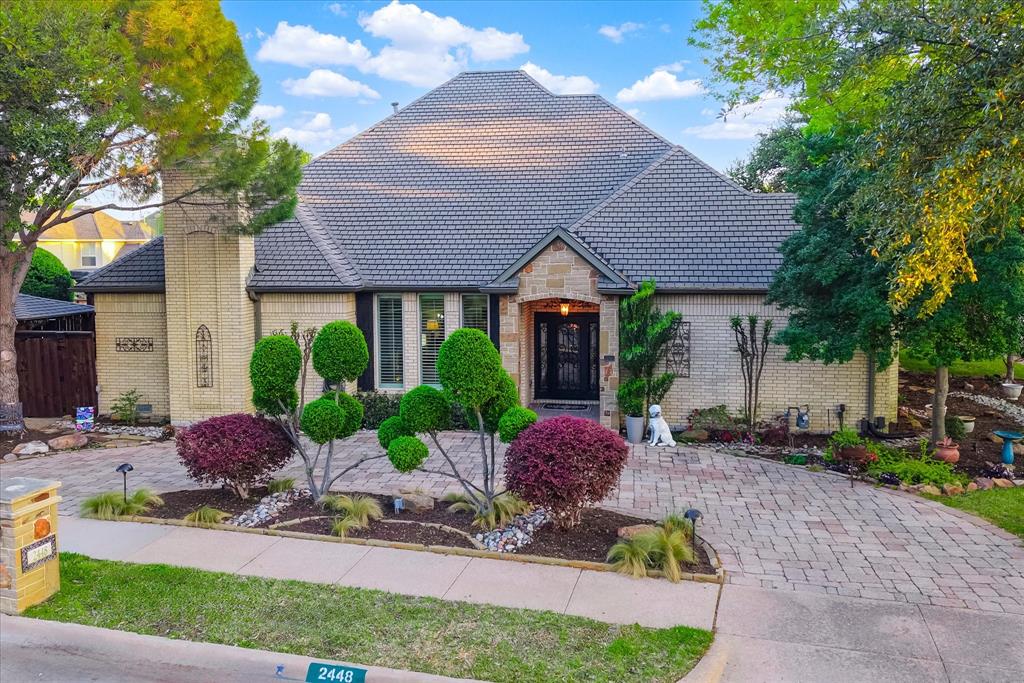 This refined single-story residence offers a seamless blend of comfort and sophistication, thoughtfully designed for modern living.  Situated on an oversized corner lot with a circular drive, the stately brick façade is enhanced by slate accents, custom iron shutters and exterior doors, manicured landscaping, and elegant evening illumination.  Inside, timeless craftsmanship is evident throughout, featuring hand-scraped hardwood floors, richly stained alder wood doors, bespoke lighting, and curated fixtures.  A welcoming foyer with classic parquet flooring sets an impressive tone. The distinguished study with built-ins offers a quiet retreat or versatile living space.  A formal dining room with crown molding and chandelier creates an intimate setting for gatherings large or small.  At the heart of the home, the open-concept great room showcases backyard views, custom built-ins, and a gas fireplace framed in travertine. An adjoining den adds flexibility, while bifold doors reveal or conceal the wet bar.  The beautifully appointed kitchen features granite countertops, breakfast bar, travertine backsplash, custom cabinetry, stainless steel appliances, and double convection ovens. Glass-front cabinetry extends into the breakfast room with pass-through to the den.  The private primary suite includes a sitting bay with plantation shutters and a spa-inspired bath with skylight, soaking tub, and glass-enclosed shower.  Two addl bedrooms, each with a full bath, provide comfort and privacy.  Step outside to a backyard oasis with synthetic turf, flagstone patio, covered deck, and cedar pergola with hot tub. Exceptional landscaping and lighting make this home a showplace day or night.  Additional highlights include energy-efficient insulated windows and gutter guards.  Schedule your showing today. Roof is GAF Elk Class 4 high performance architectural shingle inspected after every major storm.  Attic partially floored with decking. All duct work replaced approximately 2007.