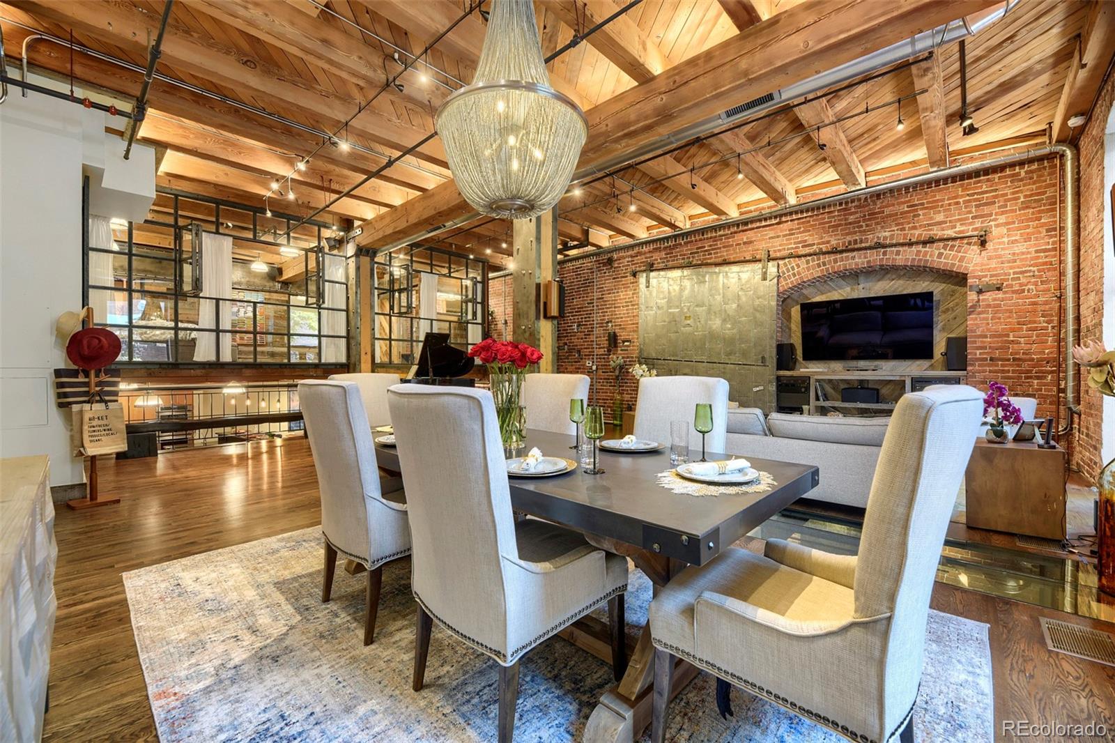 A truly one-of-a-kind urban residence, this bespoke four-level loft redefines downtown living through an experience-driven design. Originally envisioned by Denver architectural icon Dana Crawford, the home blends the scale and openness of a loft with the warmth, privacy, and comfort of a luxury residence. Unlike a typical industrial loft, each level creates its own distinct environment, offering a rare sense of separation, privacy, and purpose throughout the home. Soaring 14-foot ceilings, south-facing windows, and artistic glass floor elements allow natural light to cascade through the residence, creating an ever-changing interplay of light, volume, and architectural artistry. A lush, professionally landscaped patio with mature trees and greenery provides a private outdoor sanctuary so quiet and secluded you'll forget you're in the heart of downtown Denver, steps from Union Station.The main (Level 2) features a grand dining room with custom chandelier, entertaining space, and a versatile area ideal for a grand piano, art studio, or home office. Savant home automation seamlessly integrates lighting, climate, entertainment, and security from your mobile device. Your primary suite (Level 1) offers a walk-in closet and spa-inspired five-piece bath with an oversized programmable multi-jet shower. Level 3 is designed for entertaining, the residence features two fully equipped kitchens, including a commercial-grade chef's kitchen on the lower level with dual sinks, wine cooler, ice machine, and oversized island. Level 4 boasts a second primary bedroom with ensuite bathroom/steam room and a third bedroom currently configured as a private theater. Additional amenities include a whole-house sound system, water purification system, commercial-grade appliances, custom storage, and integrated security safe. HOA amenities boast unobstructed south and west-facing views of the Denver skyline and Rocky Mountains, complete with luxury outdoor furnishings, gas grill, and smoker.