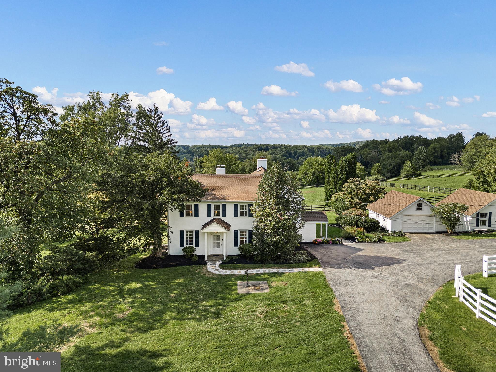 Nestled on 26 picturesque acres in the heart of sought-after Chester Springs, this exceptional equestrian estate offers a rare blend of historic charm, modern updates, and outstanding equestrian facilities. Tucked away at the end of a peaceful country lane, the circa-1850 farmhouse enjoys breathtaking views of rolling countryside, lush paddocks, and grazing horses. A stone walkway leads to the welcoming front entrance and into the original section of the home, where timeless character abounds with deep windowsills, built-in shelving, and a cozy wood-burning fireplace in the formal living room. The home flows effortlessly into a sun-filled dining room highlighted by a wall of windows framing panoramic farm views. The recently updated kitchen is designed for both everyday living and entertaining, featuring granite countertops, freshly painted cabinetry, a center island with open shelving, wine refrigerator, and convenient mudroom entry. Adjacent to the kitchen, the inviting family room offers custom built-ins, a second wood-burning fireplace, and sliding glass doors leading to a four-season sunroom that beautifully captures the surrounding landscape. Step outside to the patio and enjoy the tranquility of country living. The first floor also includes a laundry room and half bath. Upstairs, the spacious primary suite features an adjoining bath, accompanied by three additional bedrooms and a hall bath. A second staircase provides convenient access to the main level. Equestrians will appreciate the thoughtfully designed 8-stall barn, complete with oversized stalls, a new wash stall, tack room, and feed room. Currently configured as a breeding operation, the farm includes five fenced paddocks with automatic waters, two run-in sheds, and newer vinyl fencing throughout for safety and ease of maintenance. Three dry-lot paddocks provide an ideal space for rehab or specialized turnout needs. New Upgrades and Updates from 2017-2026! Farm offers a Diesel Generator! Surrounded by scenic countryside and protected woodlands, the property offers exceptional privacy and a level area well-suited for the arena of your choice.  Located just minutes from Ludwig's Corner, shopping, dining, and major transportation routes, this remarkable farm presents a rare opportunity to own a premier Chester County equestrian property and continue its legacy for generations to come.