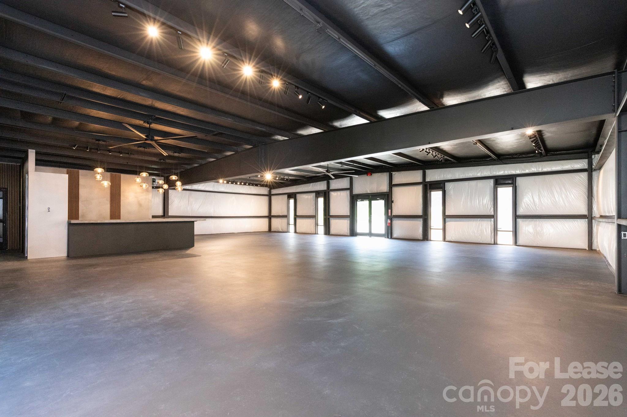 Now available for lease, 22 Stoner Road offers a unique opportunity to establish your business in Asheville’s growing Swannanoa River Corridor, just one mile from Historic Biltmore Village and surrounded by new residential development. This approximately 3,000-square-foot commercial space features an open, flexible layout well suited for an event venue, wine bar, brewery, taproom, restaurant concept, coffee shop, retail boutique, professional office, showroom, gallery, wellness studio, company headquarters, or other creative commercial use. An assembly permit has already been issued, making the property especially attractive for hospitality, entertainment, and gathering-space concepts. For businesses needing more traditional office space, the owner also has several professionally designed floor plans showing options for dividing the building into multiple private offices while maintaining shared common areas and other functional space. One preliminary layout illustrates as many as five individual offices, giving a future tenant additional flexibility to configure the property for their specific business needs. Extensively reconstructed following Hurricane Helene, the building was rebuilt using commercial-grade, flood-resistant materials and engineered construction methods designed for durability and reduced maintenance. Interior walls are finished with VRR Plus vinyl-faced insulation, creating a clean industrial look while providing vapor control and radiant-barrier benefits. The building is also wired for infrared heating, with options for gas radiant heating and cooling. The space was designed with hospitality and entertaining in mind and includes a custom bar, commercial wash sink, separate handwashing sink, ADA-compliant restroom, smart wall-mounted bathroom heaters, illuminated smart mirrors, and a commercial-grade dishwasher currently available through a rental arrangement. The open floor plan provides plenty of flexibility for tables, bar seating, lounge areas, retail displays, workstations, private offices, or live entertainment. A dedicated food truck hookup with 50-amp electrical service and water gives a tenant the ability to offer or partner with food service without taking on the expense of immediately constructing a full commercial kitchen. The property also includes approximately 480 additional square feet of functional space outside the main building, including an electrically equipped 160-square-foot Containest office/flex space and a 320-square-foot High Cube Connex storage container. Both are permanently installed with FEMA-certified engineered tie-down systems. Whether you envision a taproom, speakeasy, event space, professional office, creative workspace, showroom, retail concept, wellness business, or something entirely different, 22 Stoner Road provides the flexibility, infrastructure, and location to bring that vision to life. Bring your concept. Make the space your own. Grow your business at 22 Stoner Road.